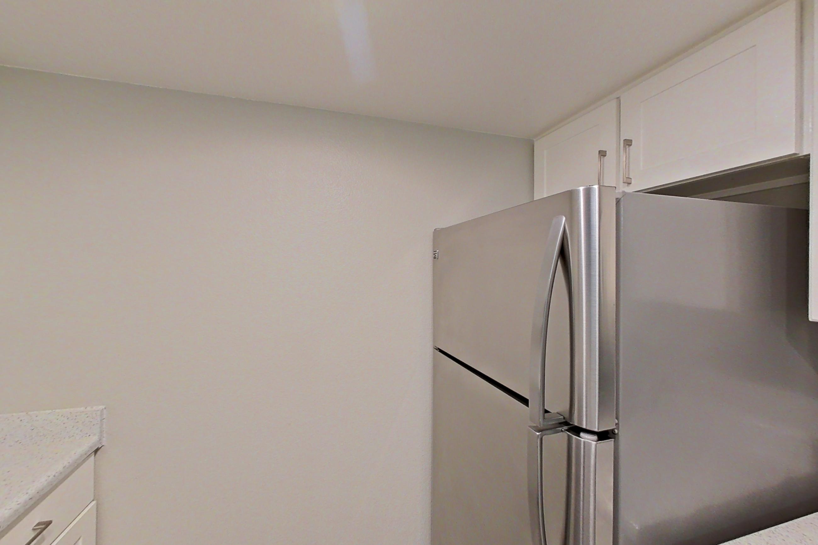 Kitchen with dishwasher, electric range, light stone countertops, light wood-finish flooring, microwave, oven/range, range hood, refrigerator, and stainless steel appliances, Apartment 18 at Avana Rancho Cucamonga