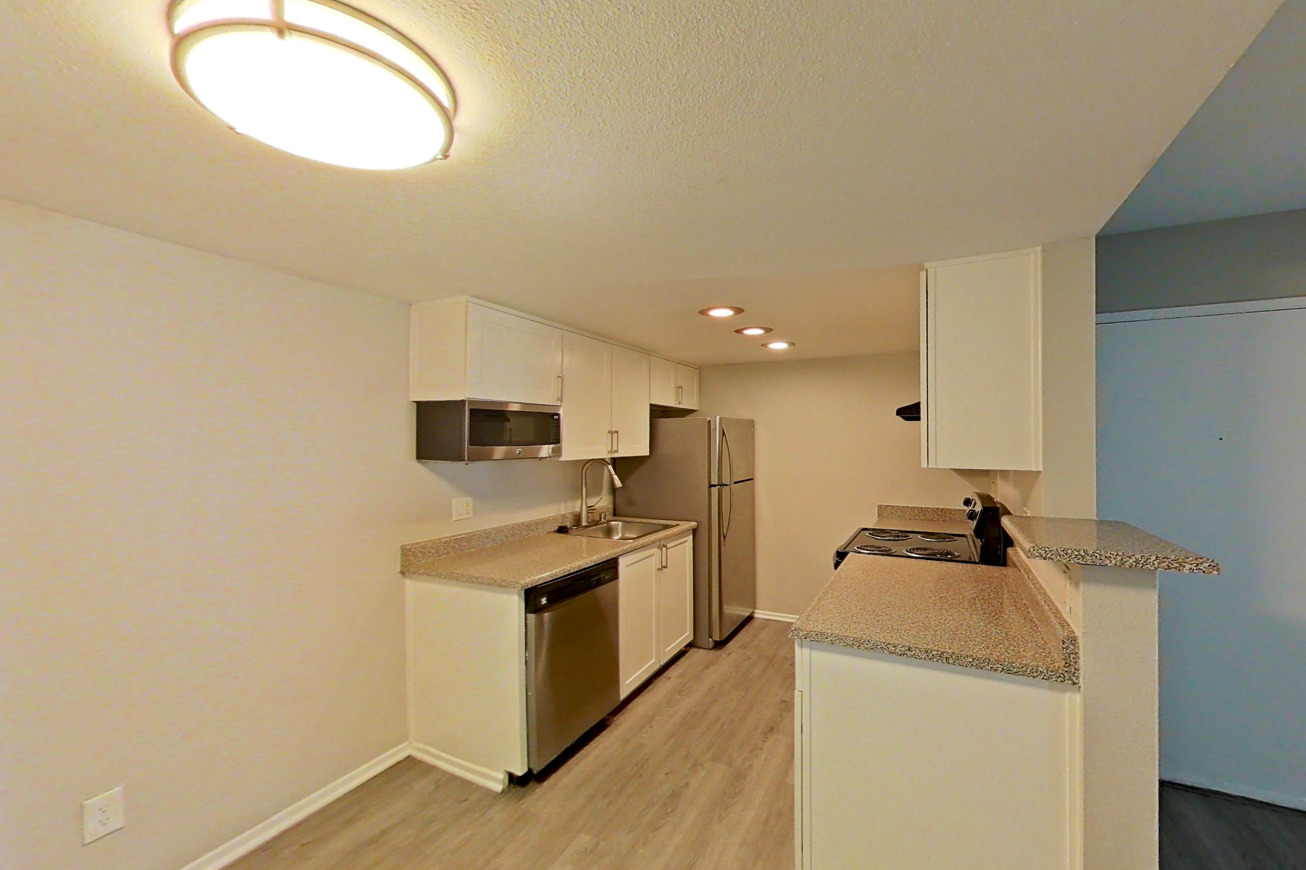 Dining area with dishwasher, light countertops, light wood-finish flooring, refrigerator, and stainless steel appliances, Apartment 02 at Avana Rancho Cucamonga