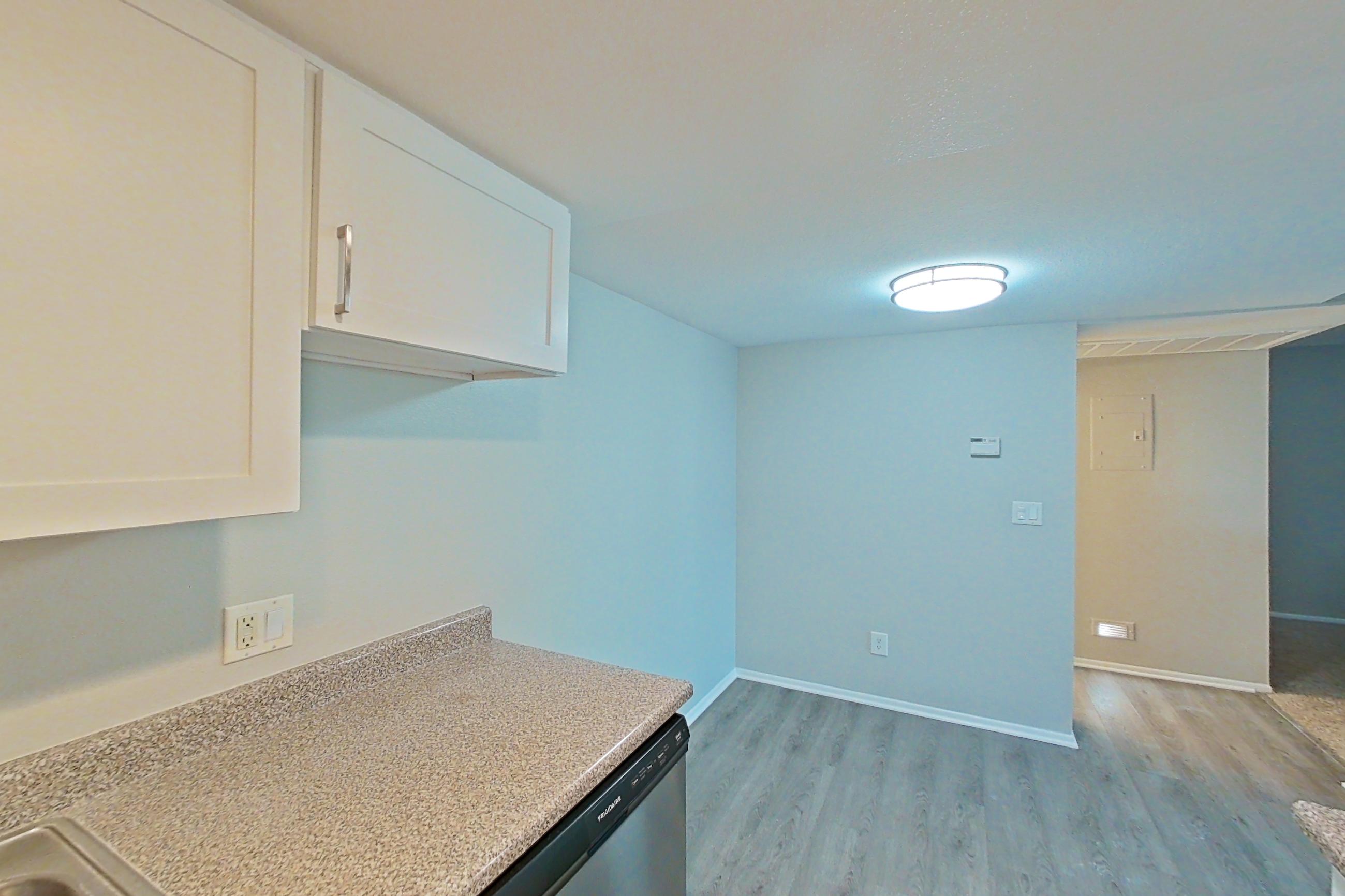 Kitchen with black appliances, dishwasher, electric range, light countertops, light stone countertops, light wood-finish flooring, microwave, oven/range, refrigerator, and stainless steel appliances, Apartment 06 at Avana Rancho Cucamonga
