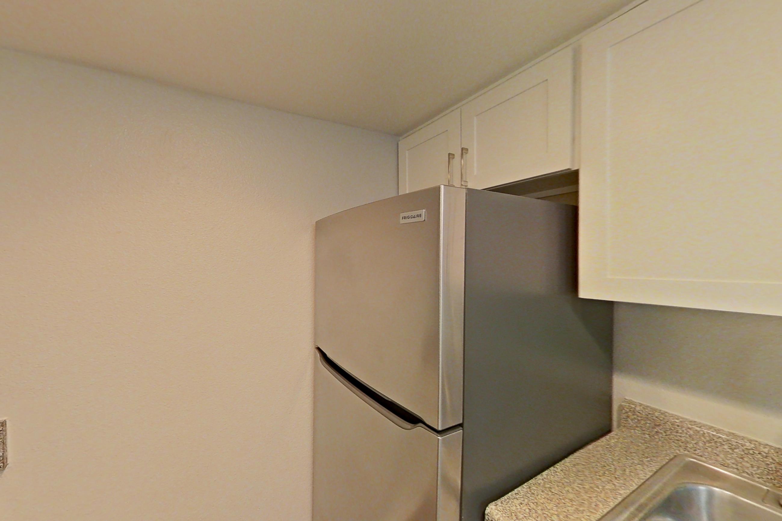 Kitchen with black appliances, dishwasher, electric range, light countertops, light stone countertops, light wood-finish flooring, microwave, oven/range, refrigerator, and stainless steel appliances, Apartment 06 at Avana Rancho Cucamonga