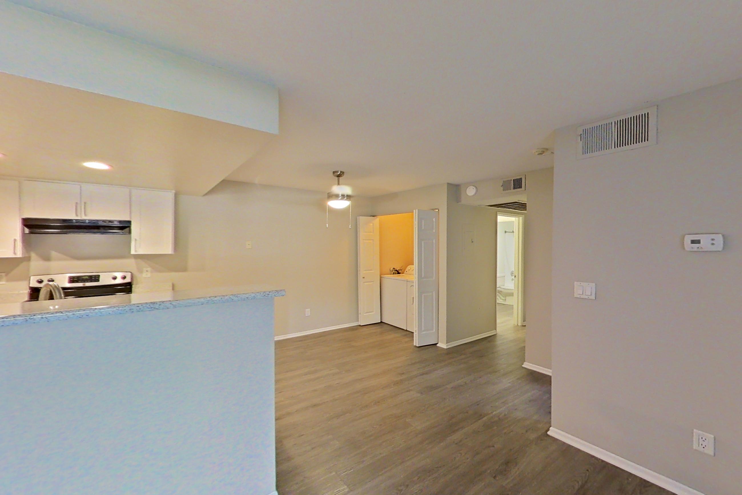 Living room with dark wood-finish flooring, in-unit laundry, oven/range, and stainless steel appliances, Apartment 02 at Avana Rancho Cucamonga