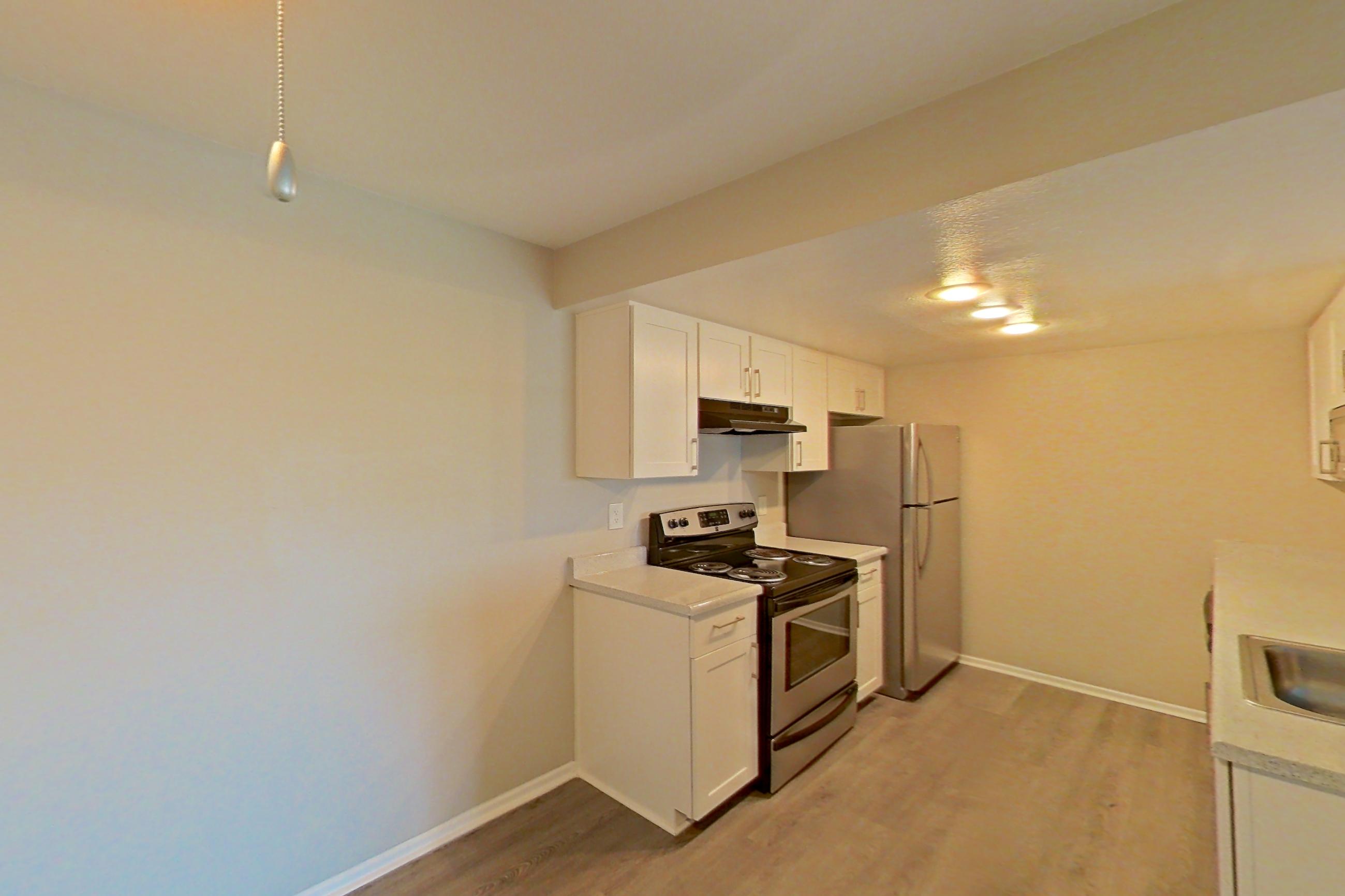 Dining area with dark wood-finish flooring, electric range, light countertops, light wood-finish flooring, oven/range, range hood, refrigerator, stainless steel appliances, and white appliances, Apartment 05 at Avana Rancho Cucamonga