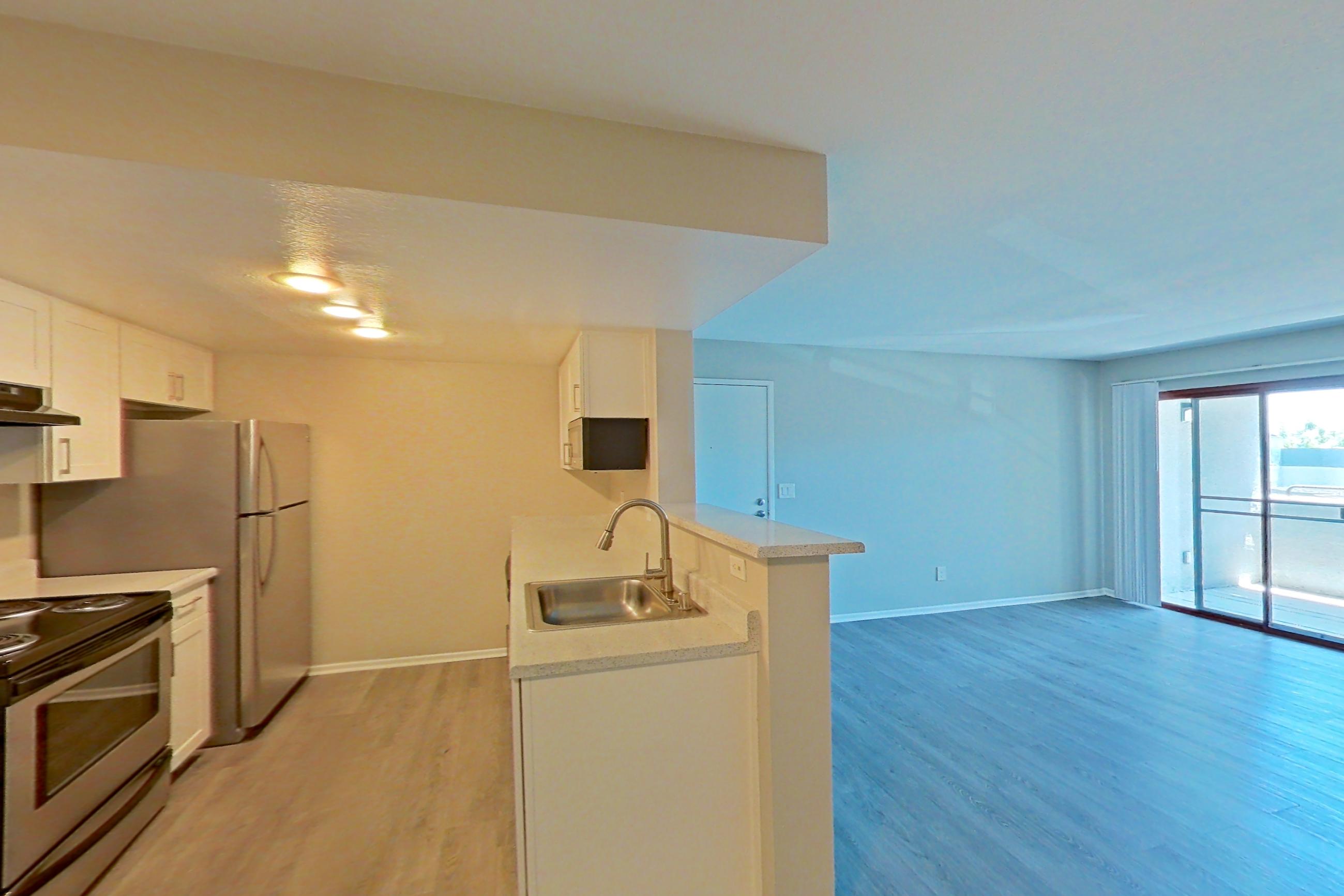 Dining area with dark wood-finish flooring, electric range, light countertops, light wood-finish flooring, oven/range, range hood, refrigerator, stainless steel appliances, and white appliances, Apartment 05 at Avana Rancho Cucamonga