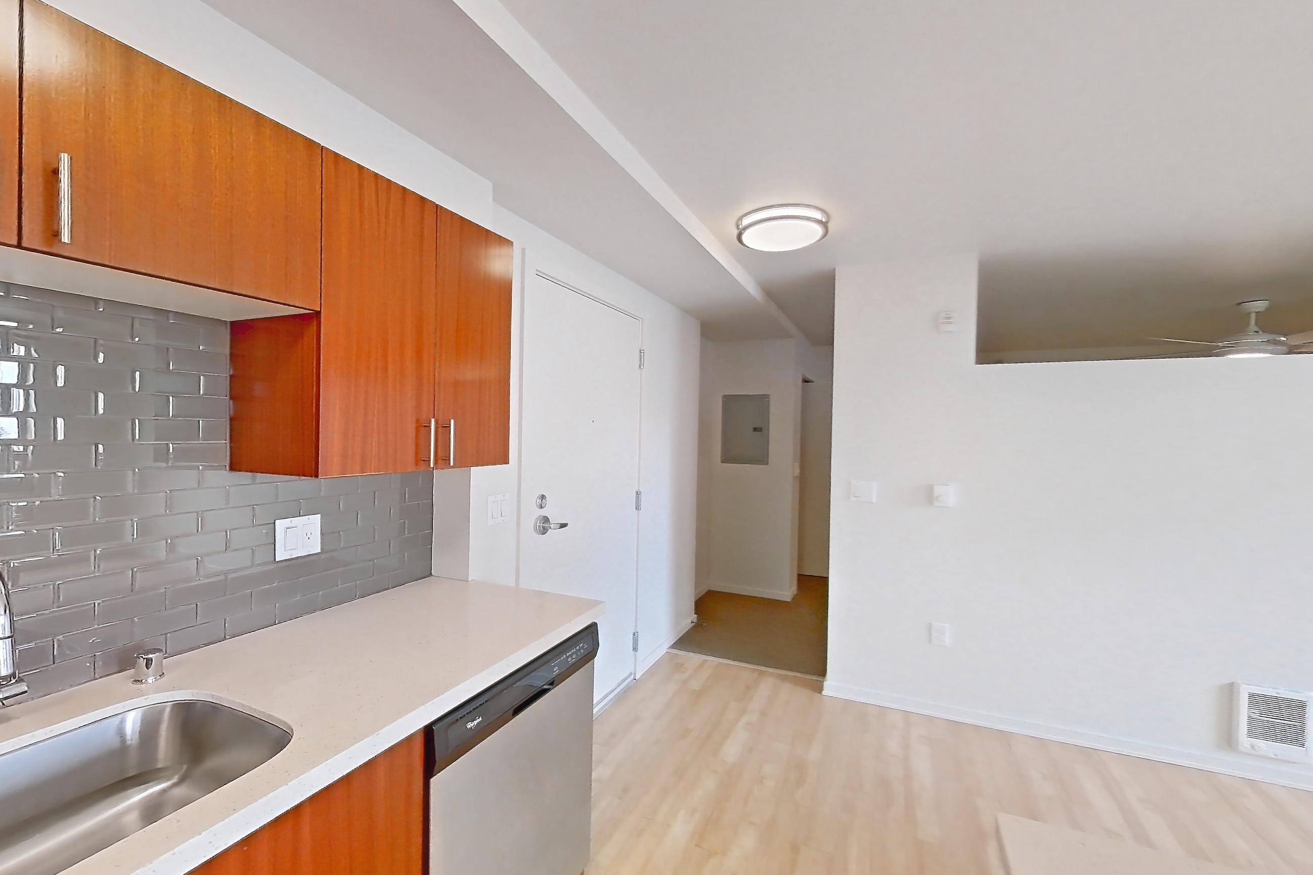 Kitchen with dishwasher, electric range, light countertops, light stone countertops, light wood-finish flooring, microwave, oven/range, refrigerator, and stainless steel appliances, Apartment L207 at Union SLU