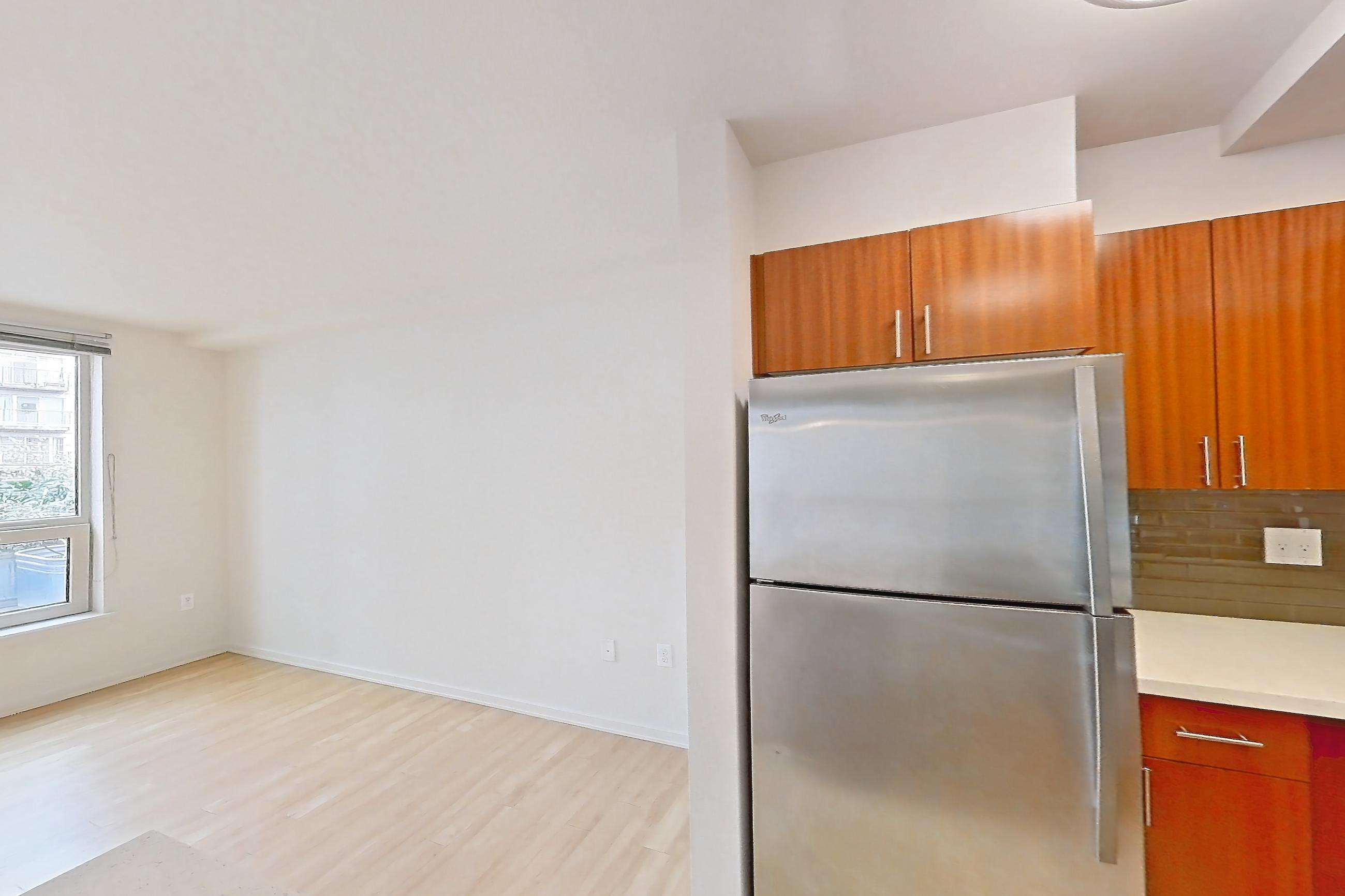 Kitchen with dishwasher, electric range, light countertops, light stone countertops, light wood-finish flooring, microwave, oven/range, refrigerator, and stainless steel appliances, Apartment L207 at Union SLU