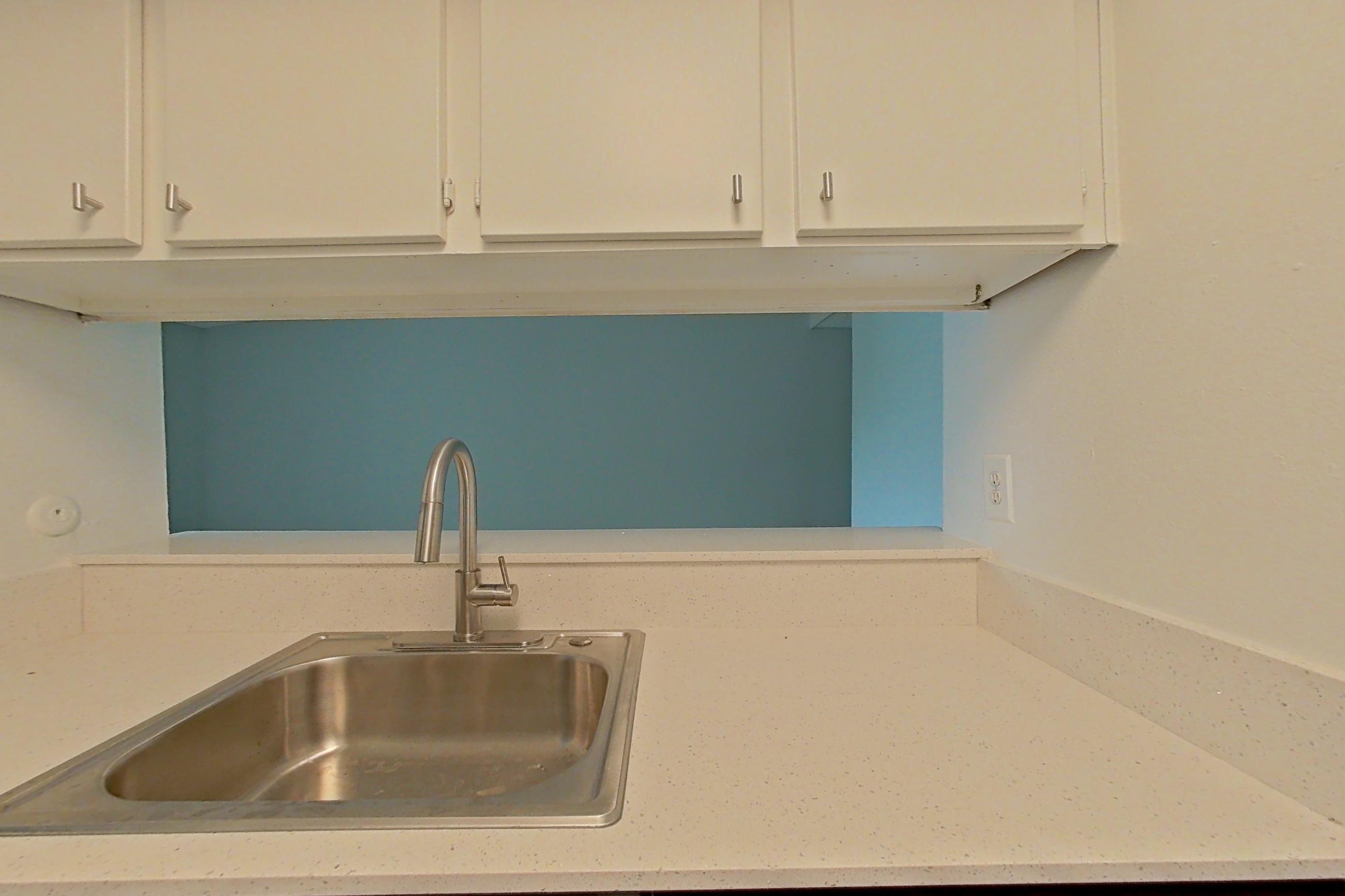 Kitchen with black appliances, dishwasher, electric range, light countertops, light stone countertops, oven/range, and stainless steel appliances, Apartment 211 at The Cove Apartments