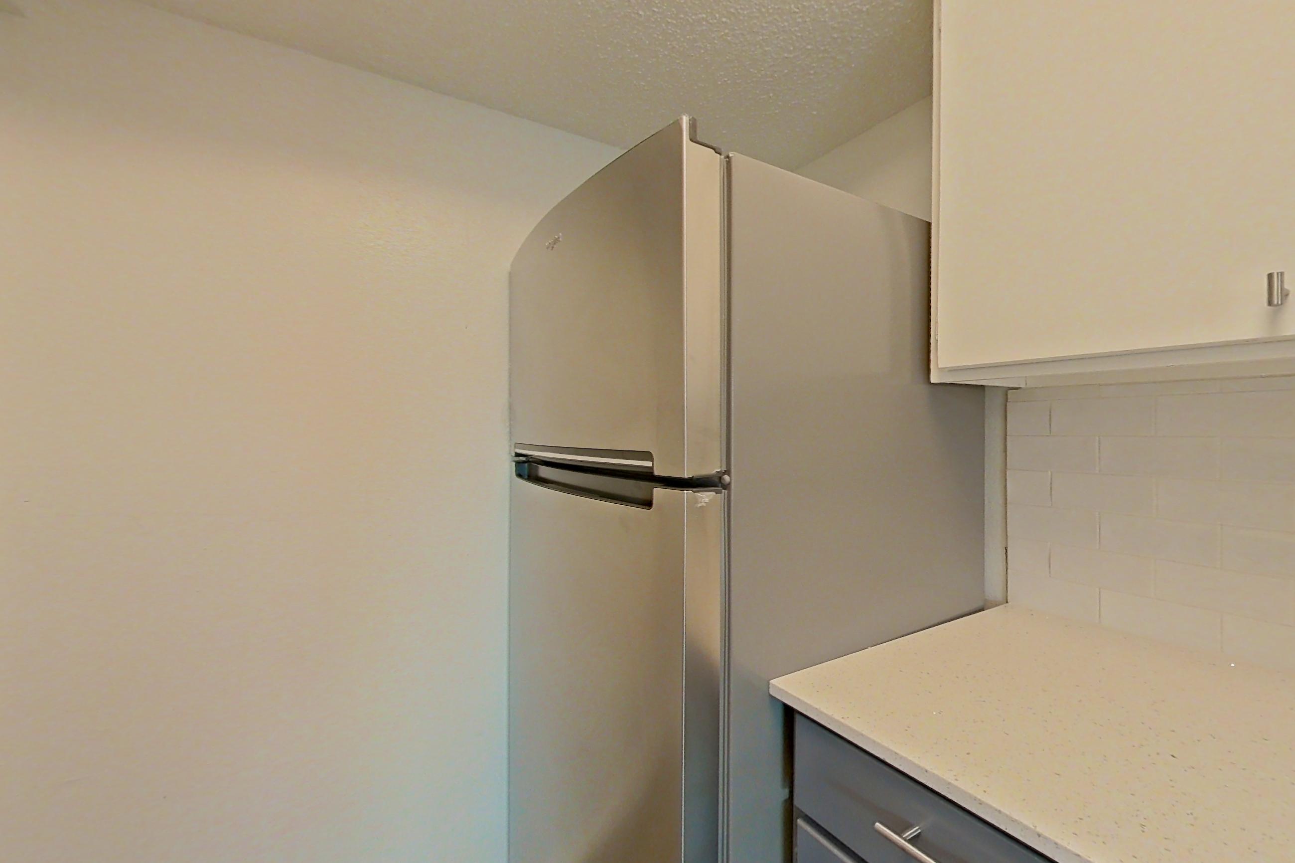 Kitchen with black appliances, dishwasher, electric range, light countertops, light stone countertops, oven/range, and stainless steel appliances, Apartment 211 at The Cove Apartments