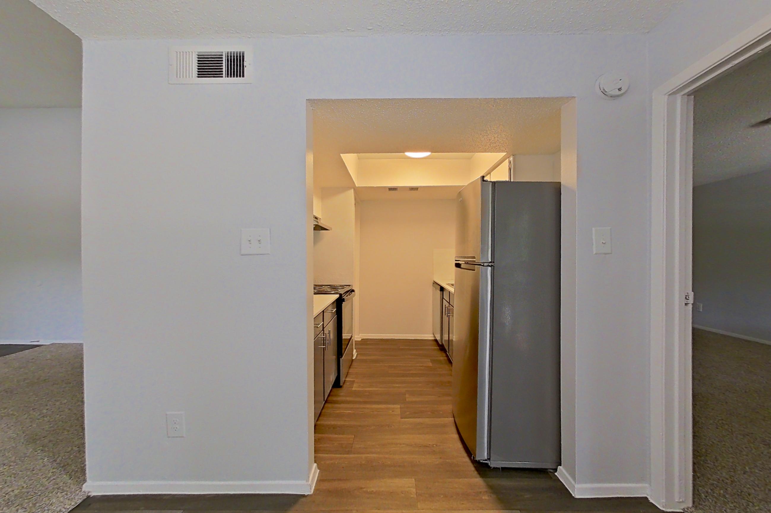 Living space with dark wood-finish flooring, fireplace, refrigerator, and stainless steel appliances, Apartment 1904 at The Cove Apartments