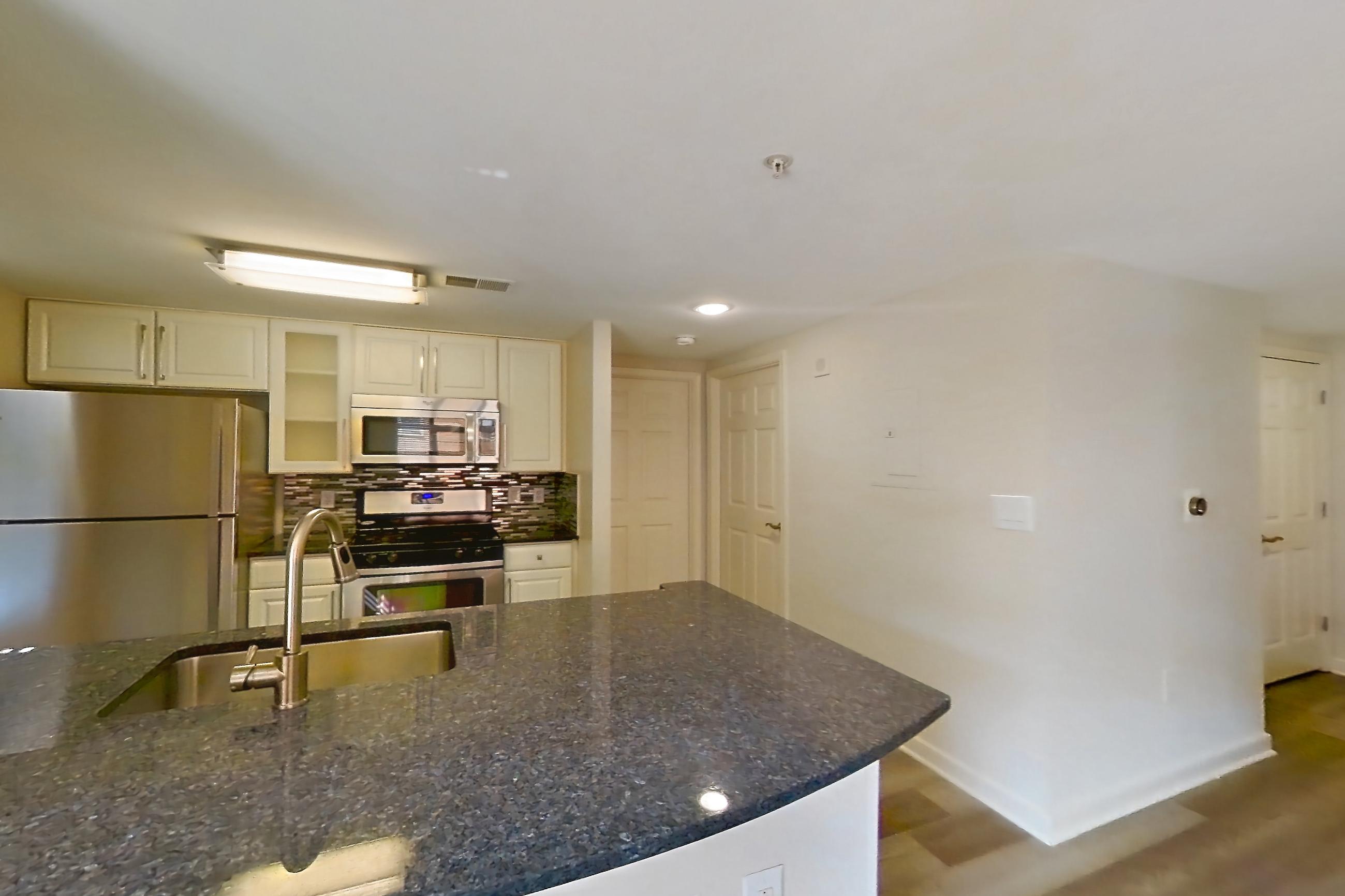 Kitchen with dark stone countertops and light wood-finish flooring, Apartment 302 at The Barton at Woodley