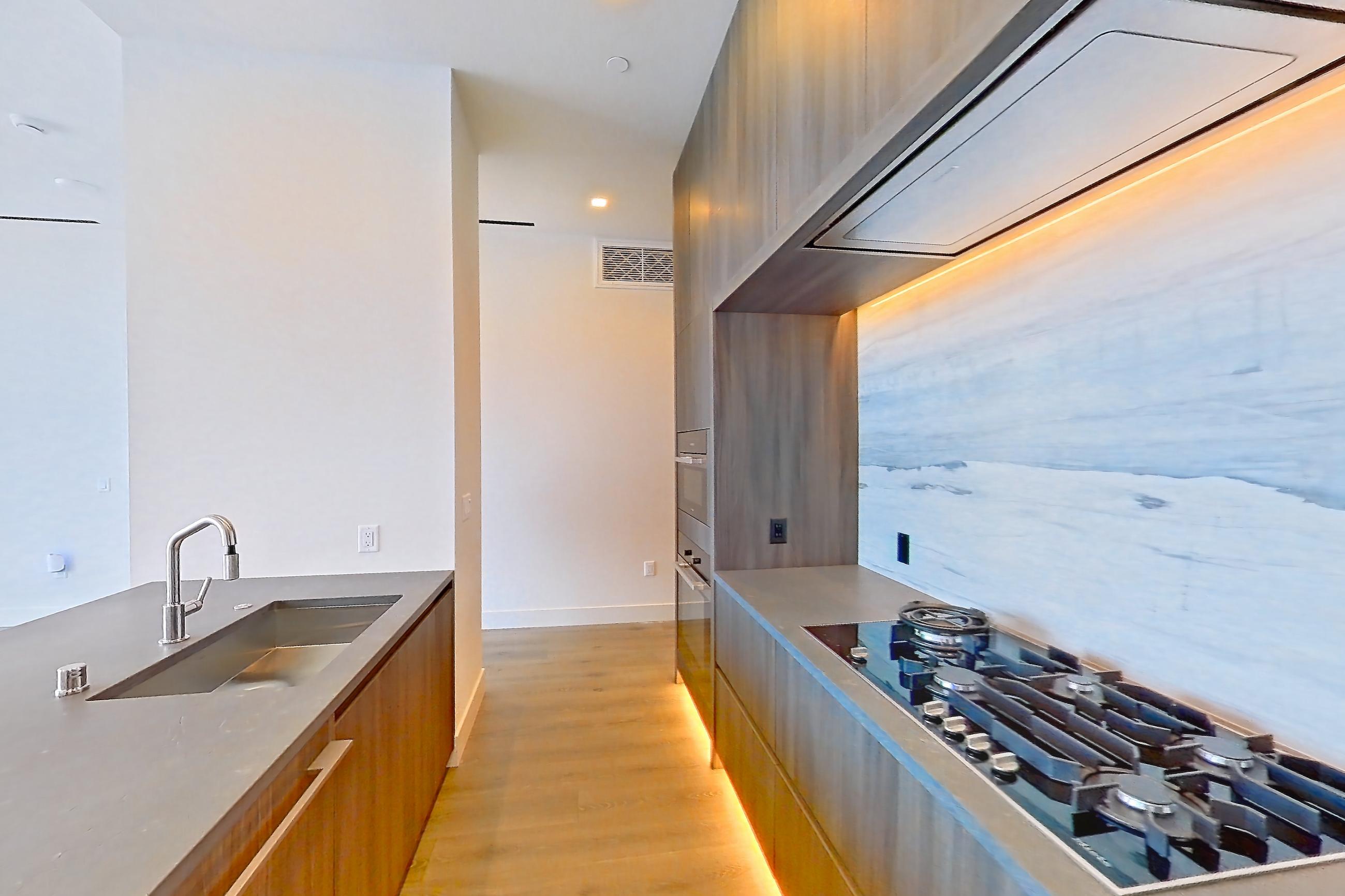 Kitchen with gas cooktop, light wood-finish flooring, and wet/dry bar, Apartment PH04 at Alloy