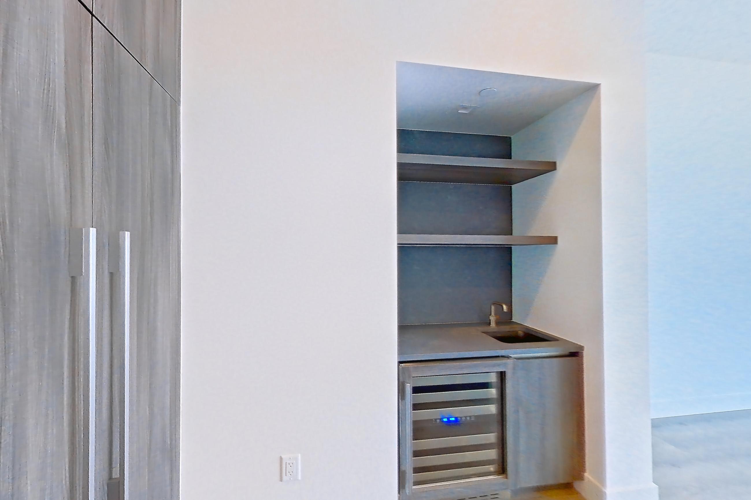 Kitchen with gas cooktop, light wood-finish flooring, and wet/dry bar, Apartment PH04 at Alloy