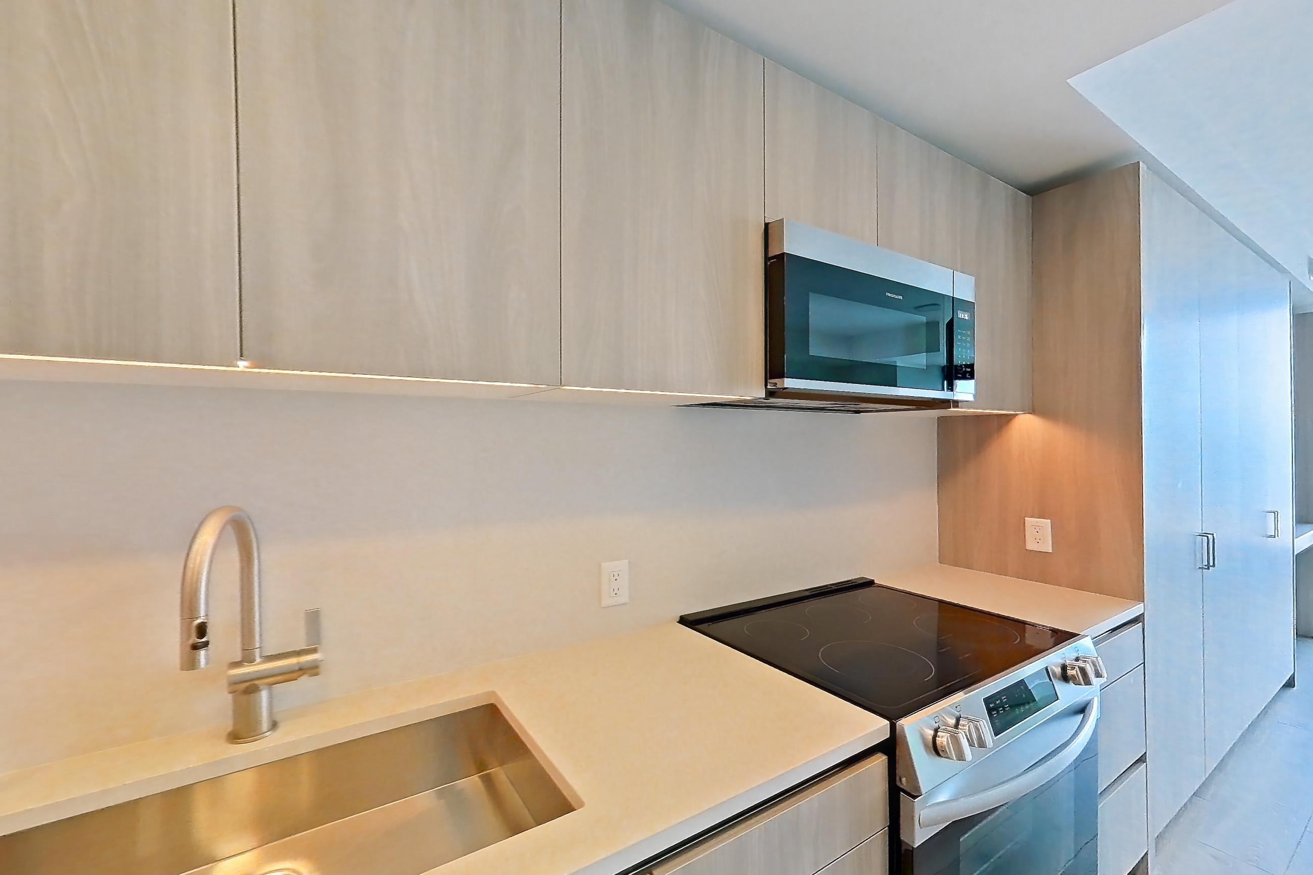 Kitchen with dishwasher, electric range, light stone countertops, light wood-finish flooring, oven/range, refrigerator, and stainless steel appliances, Apartment 1715 at Alloy