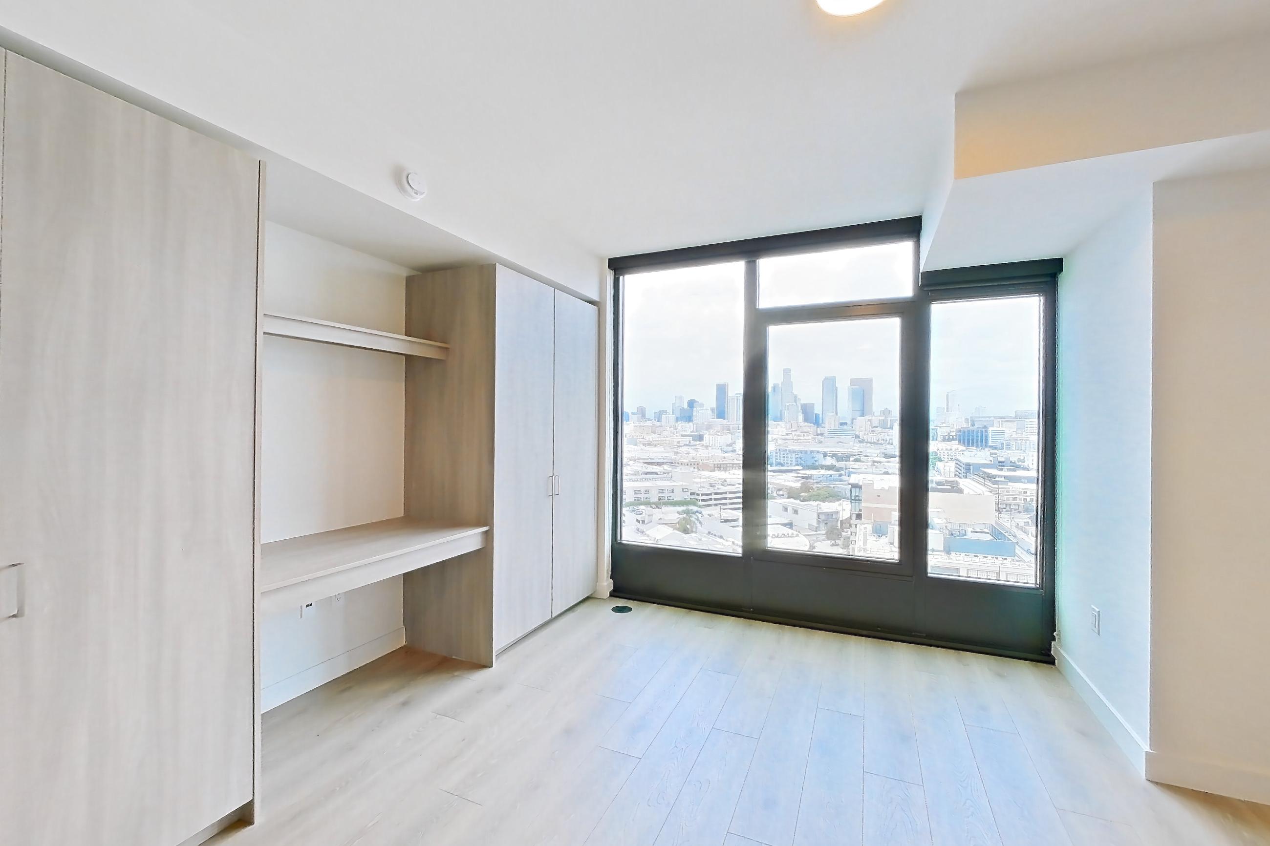Living room with electric range, light countertops, light wood-finish flooring, microwave, oven/range, and stainless steel appliances, Apartment 1715 at Alloy