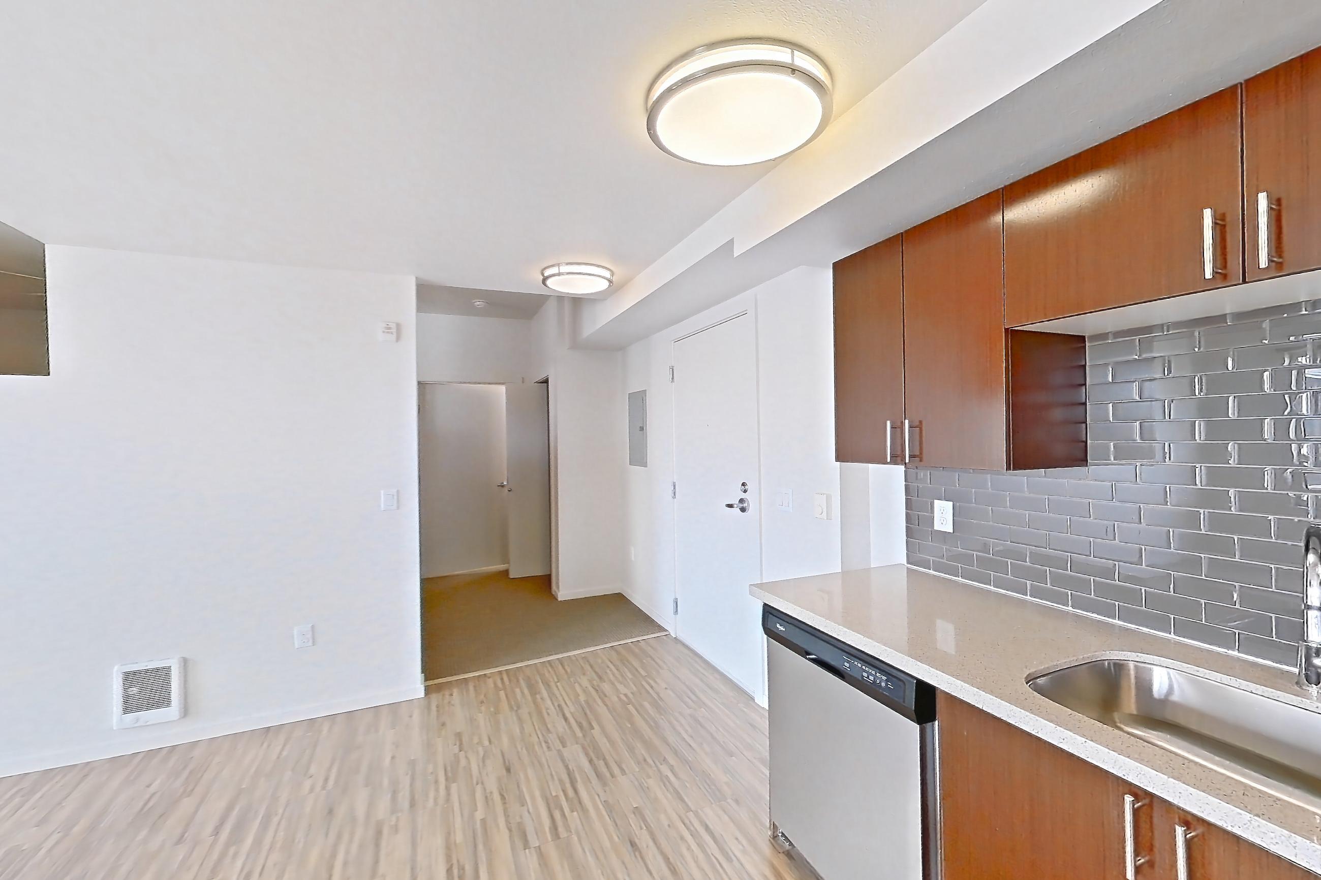 Kitchen with dishwasher, electric range, light countertops, light stone countertops, light wood-finish flooring, microwave, oven/range, refrigerator, and stainless steel appliances, Apartment L635 at Union SLU