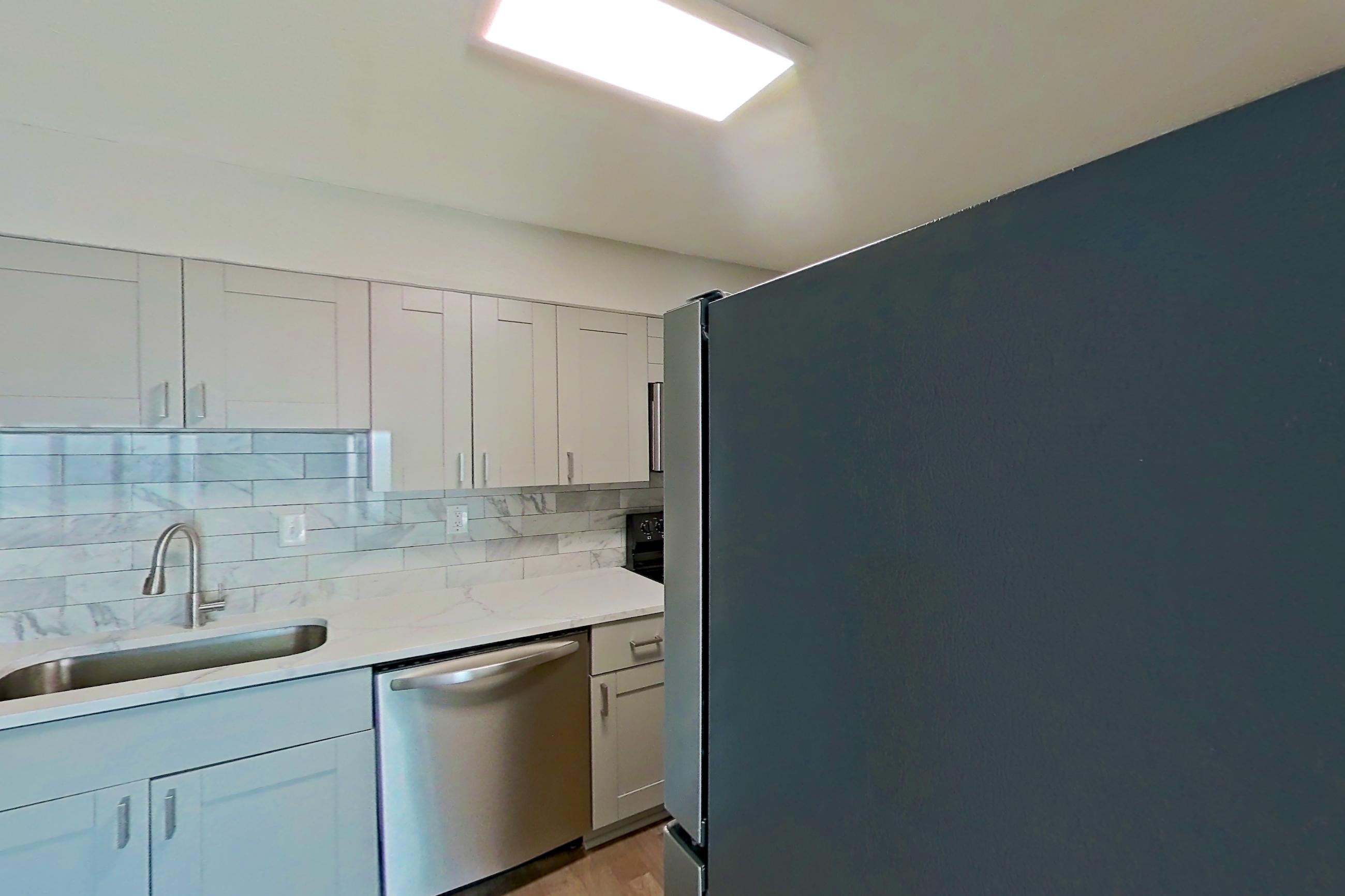Kitchen pantry with dishwasher, light stone countertops, light wood-finish flooring, refrigerator, and stainless steel appliances, Apartment 0303 at Dunwoody Glen