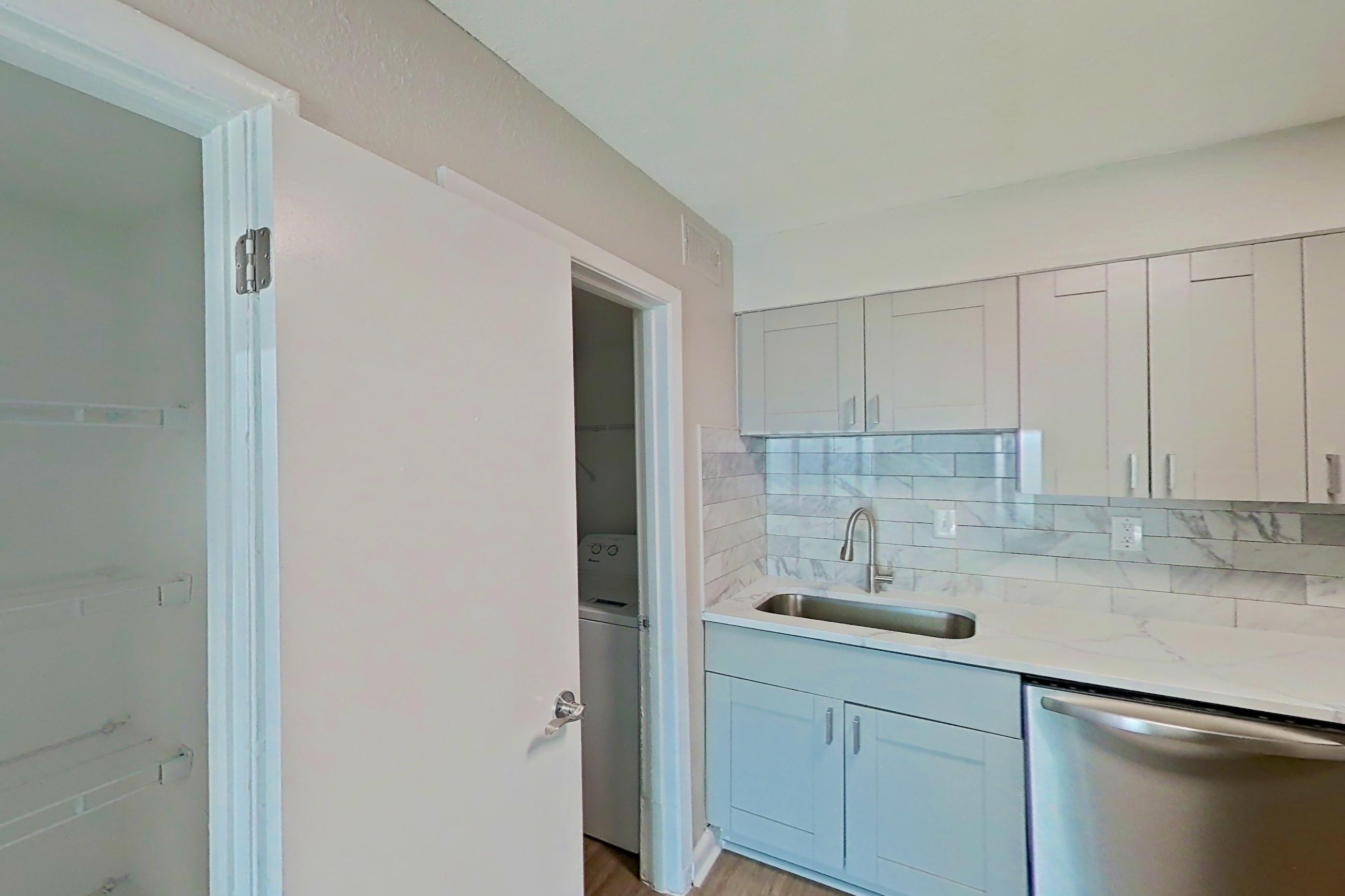 Kitchen pantry with dishwasher, light stone countertops, light wood-finish flooring, refrigerator, and stainless steel appliances, Apartment 0303 at Dunwoody Glen