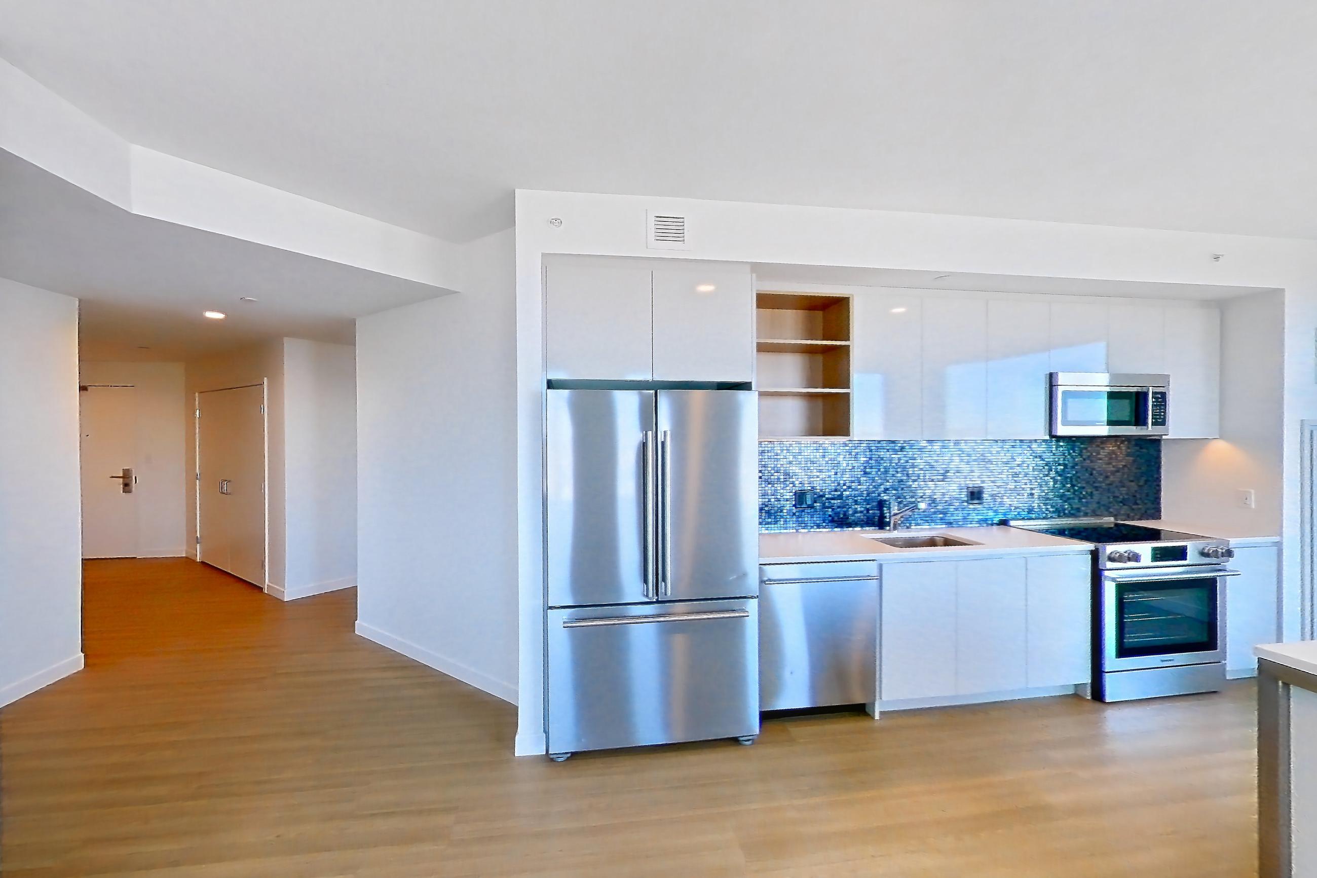 Living room 1 with dishwasher, electric range, light countertops, light wood-finish flooring, oven/range, refrigerator, and stainless steel appliances, Apartment 2802 at The Sudbury