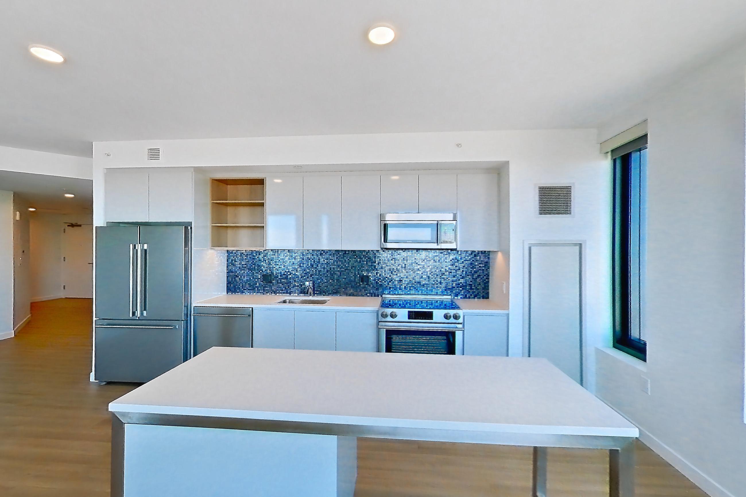Living room 2 with city view, electric range, light countertops, light wood-finish flooring, oven/range, stainless steel appliances, and water view, Apartment 2802 at The Sudbury