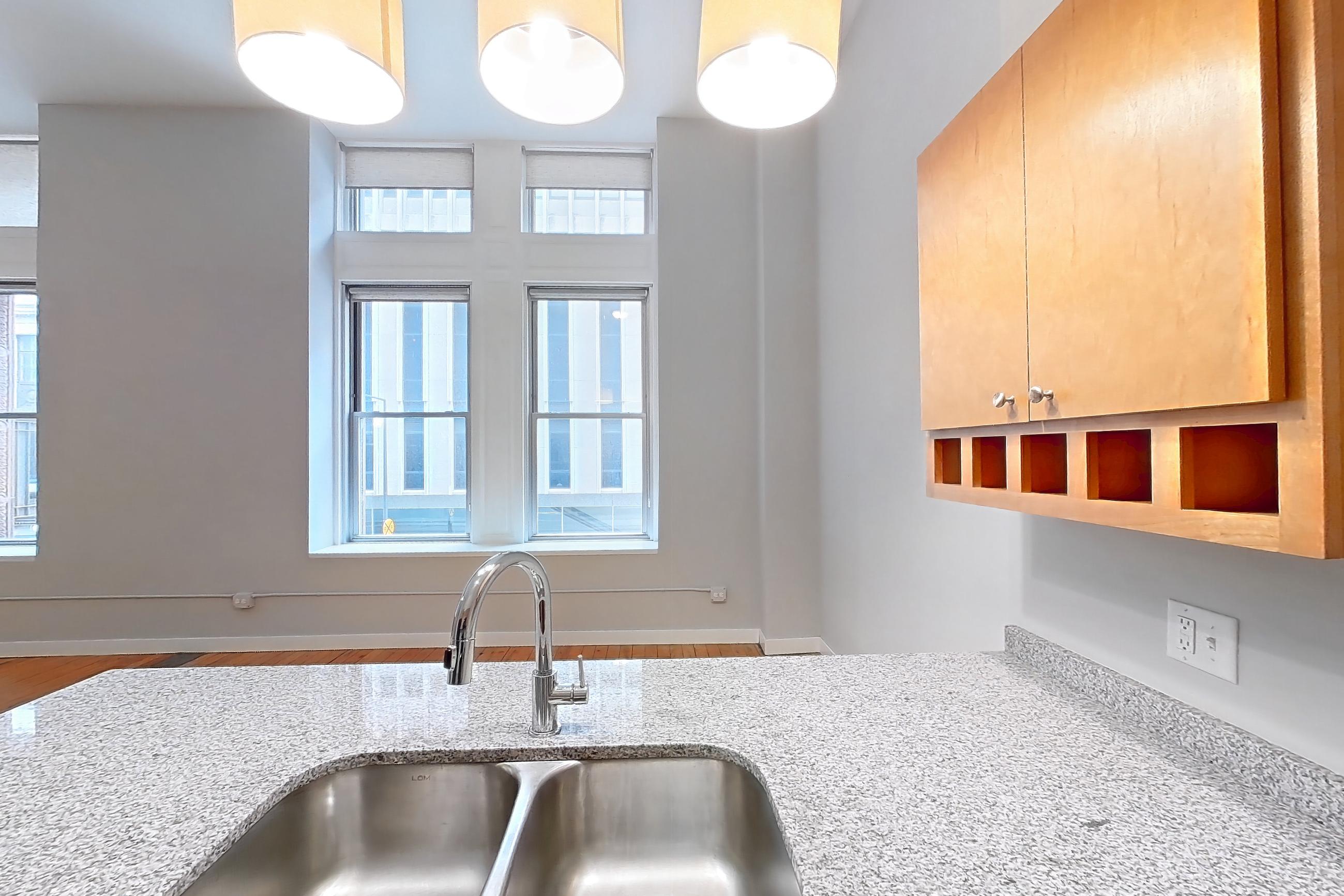 Kitchen with black appliances, dishwasher, electric range, light stone countertops, light wood-finish flooring, microwave, oven/range, refrigerator, and wood-finish flooring, Apartment 0230 at Pioneer Endicott Apartments