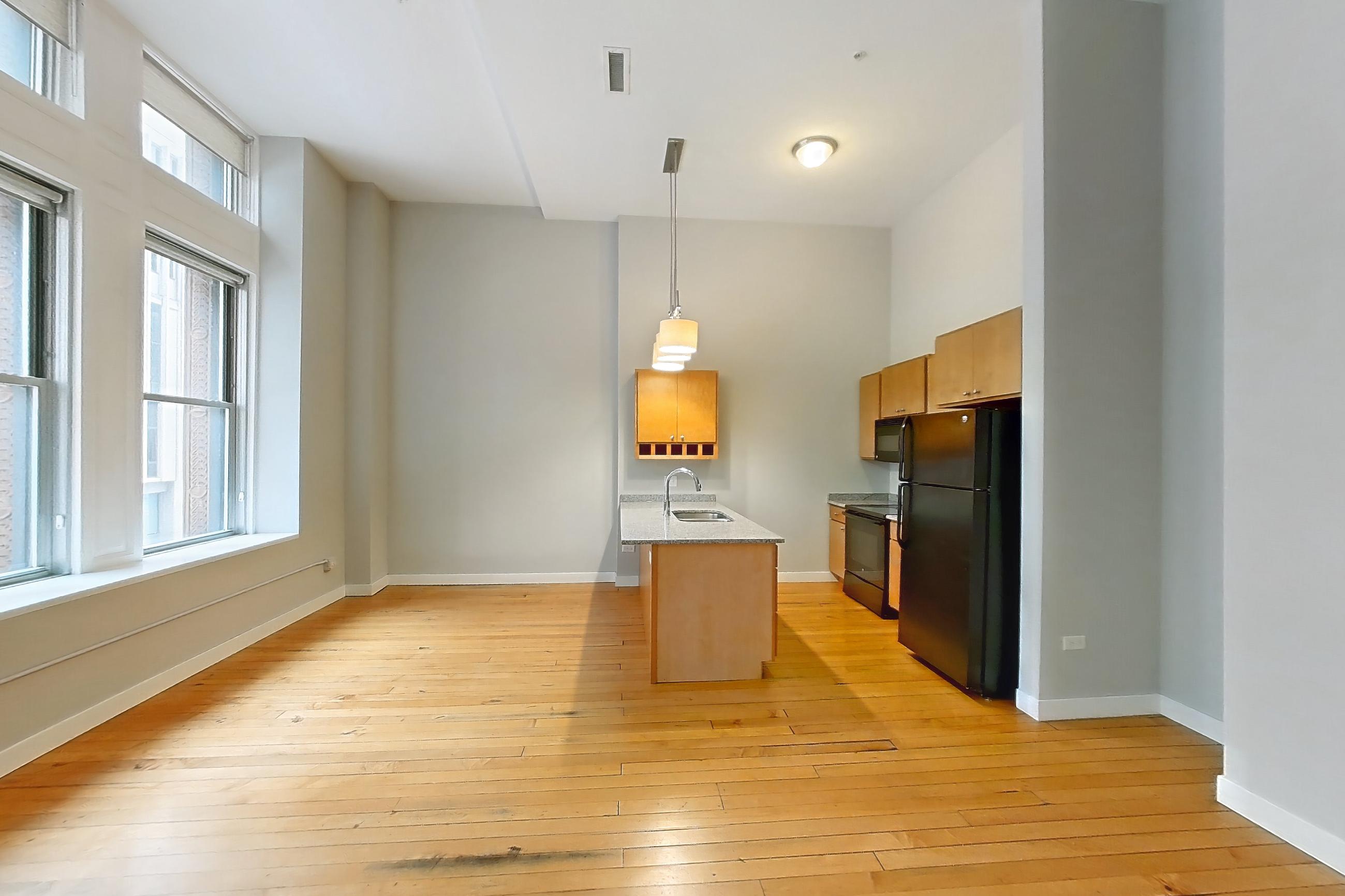 Living room with black appliances, electric range, light stone countertops, light wood-finish flooring, oven/range, refrigerator, and wood-finish flooring, Apartment 0230 at Pioneer Endicott Apartments