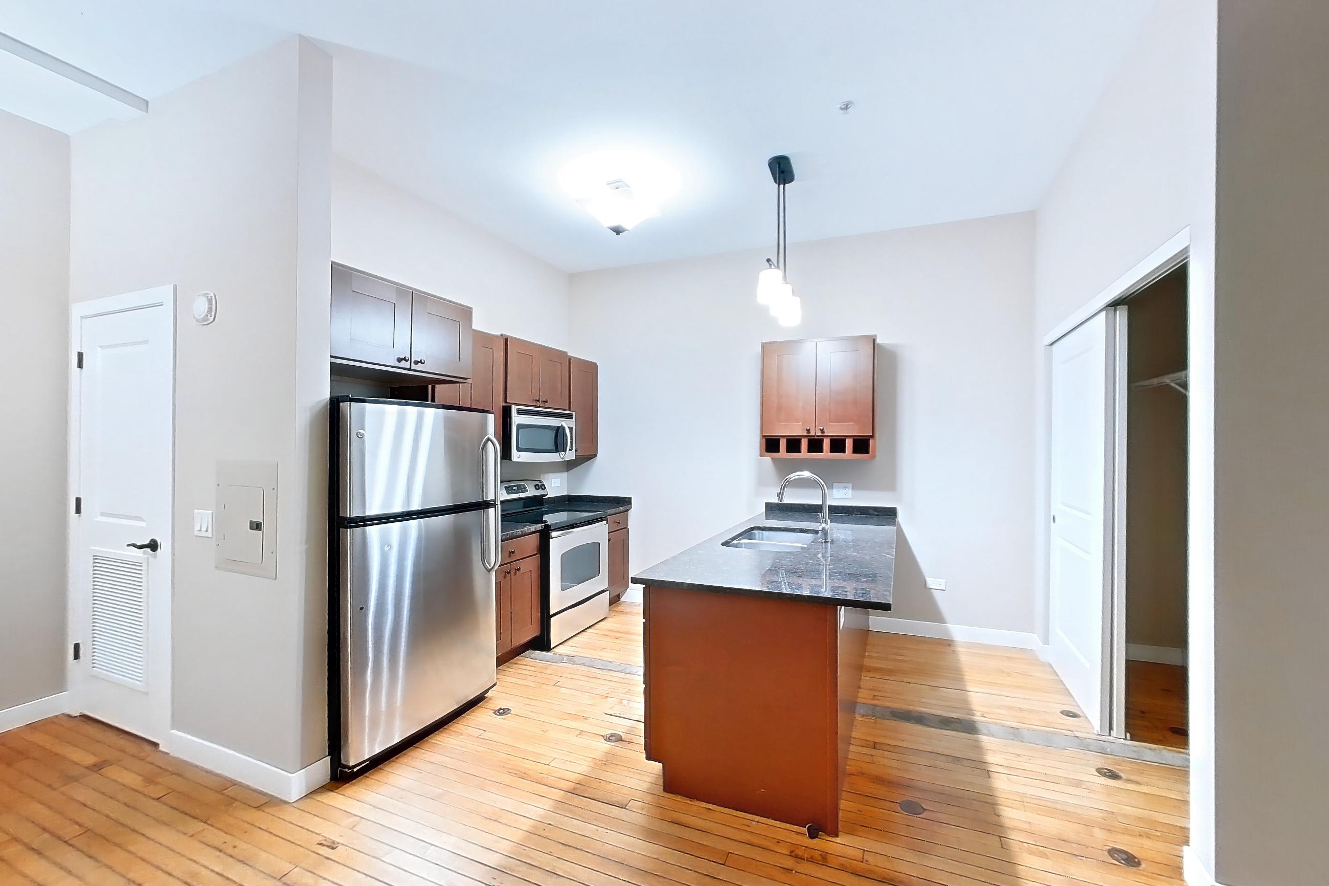 Living space with dark stone countertops, electric range, light wood-finish flooring, oven/range, refrigerator, stainless steel appliances, and wood-finish flooring, Apartment 0425 at Pioneer Endicott Apartments