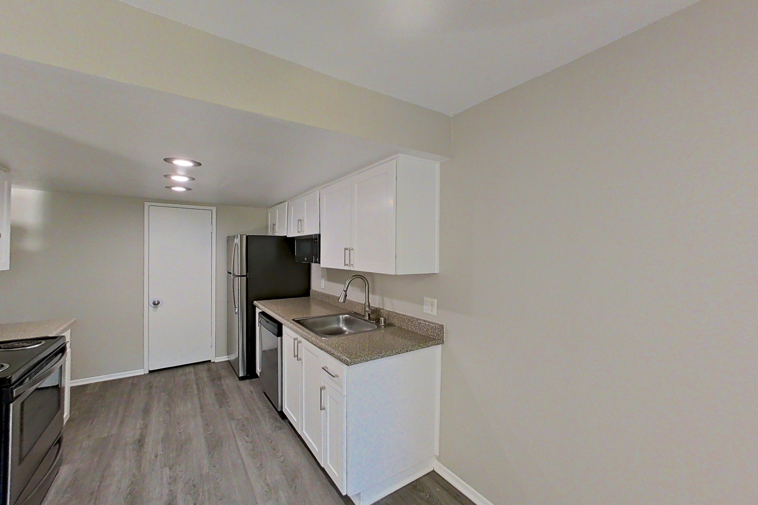 Dining area with dark wood-finish flooring, dishwasher, electric range, light countertops, light stone countertops, light wood-finish flooring, oven/range, refrigerator, and stainless steel appliances, Apartment 07 at Avana Rancho Cucamonga