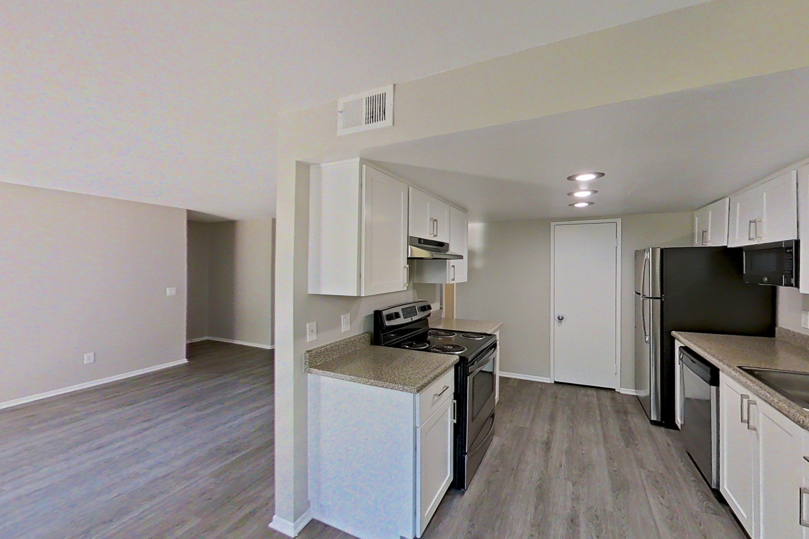 Dining area with dark wood-finish flooring, dishwasher, electric range, light countertops, light stone countertops, light wood-finish flooring, oven/range, refrigerator, and stainless steel appliances, Apartment 07 at Avana Rancho Cucamonga