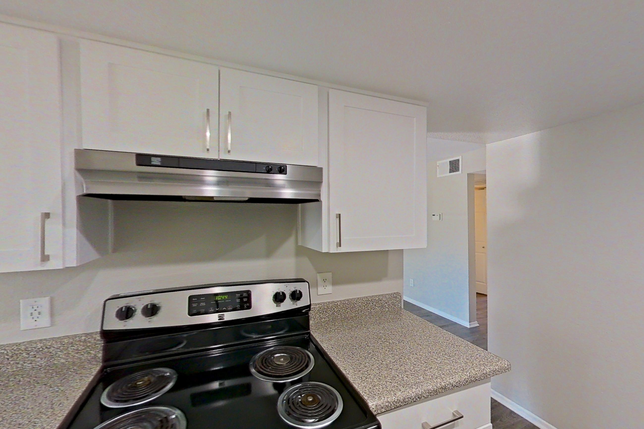 Kitchen with dishwasher, electric range, light countertops, light stone countertops, light wood-finish flooring, microwave, oven/range, refrigerator, and stainless steel appliances, Apartment 07 at Avana Rancho Cucamonga