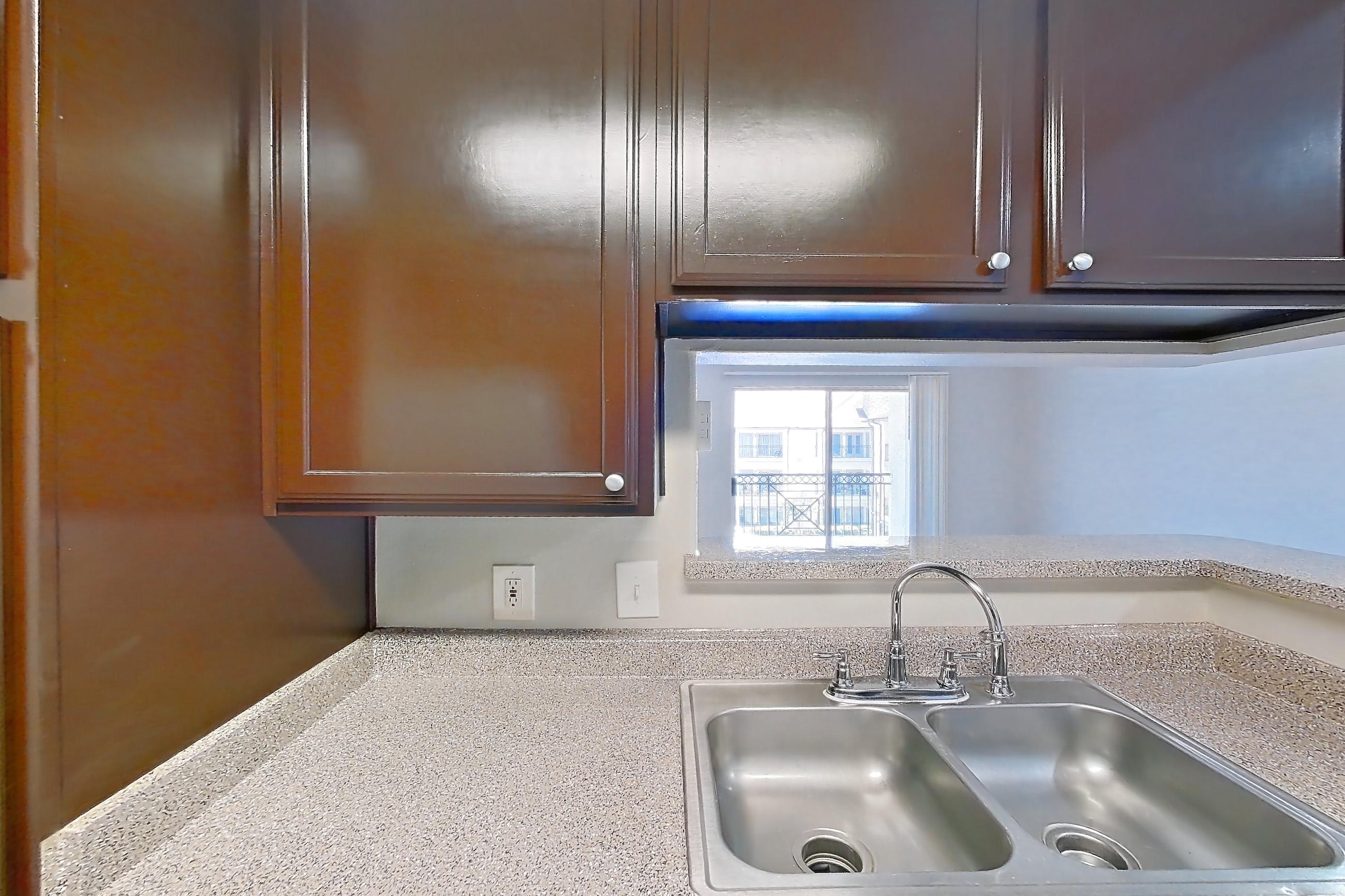 Kitchen with dishwasher, electric range, light countertops, light stone countertops, light wood-finish flooring, oven/range, range hood, refrigerator, stainless steel appliances, white appliances, and wood-finish flooring, Apartment 0131 at Marquis on Westheimer