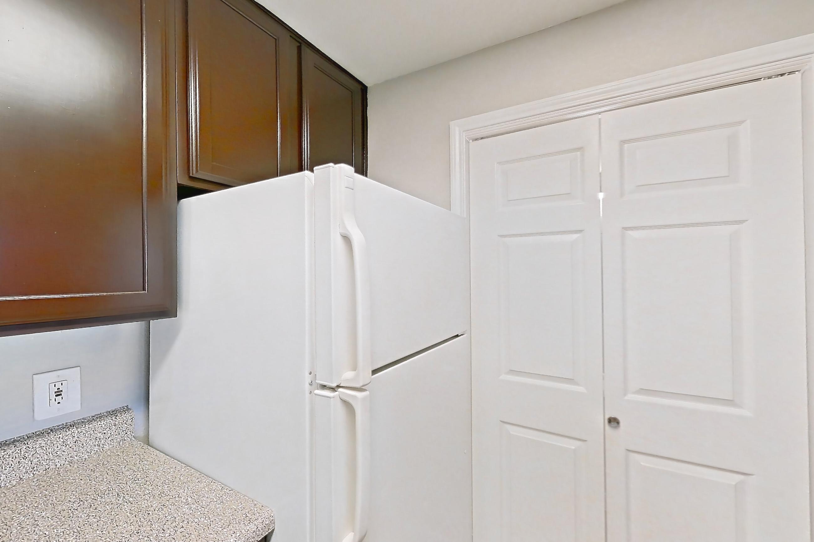 Kitchen with dishwasher, electric range, light countertops, light stone countertops, light wood-finish flooring, oven/range, range hood, refrigerator, stainless steel appliances, white appliances, and wood-finish flooring, Apartment 0131 at Marquis on Westheimer