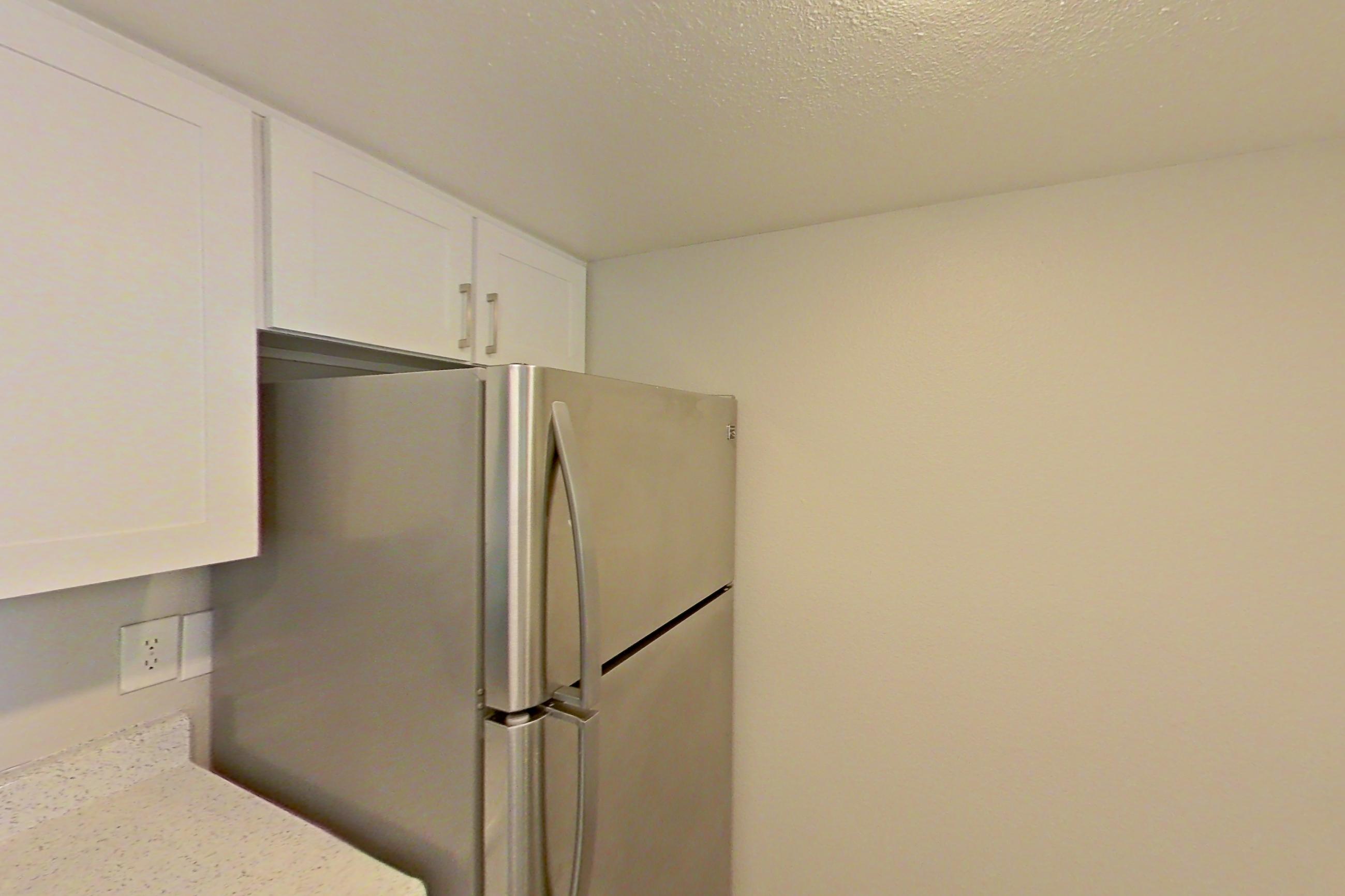 Kitchen with electric range, light stone countertops, light wood-finish flooring, microwave, oven/range, refrigerator, and stainless steel appliances, Apartment 24 at Avana Rancho Cucamonga