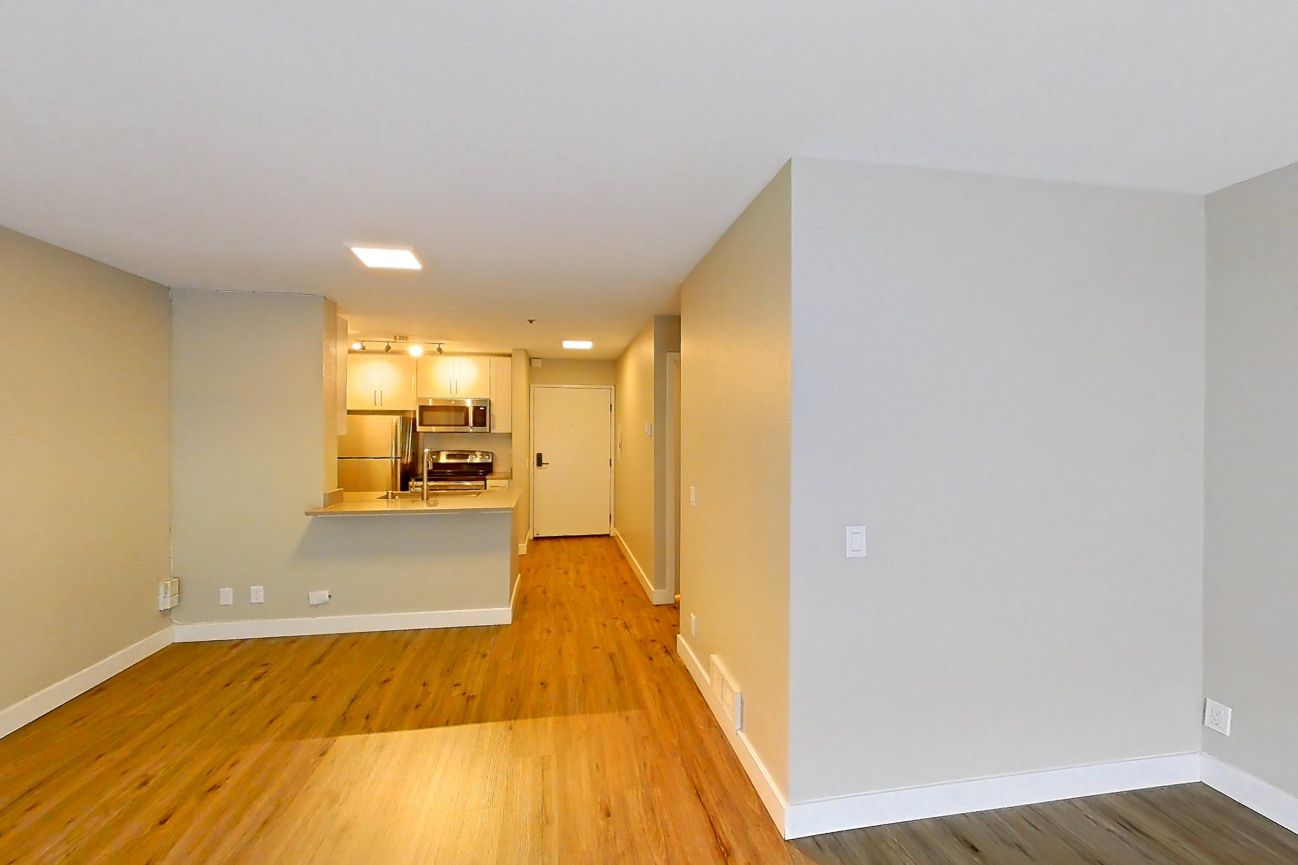 Living space with light wood-finish flooring, oven/range, refrigerator, stainless steel appliances, and white appliances, Apartment 7-115 at Bayside Village