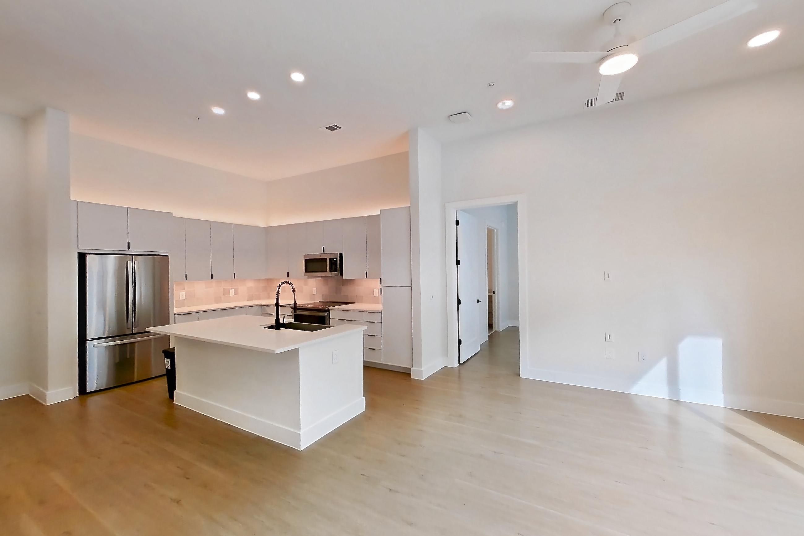 Dining room with electric range, kitchen island, light countertops, light wood-finish flooring, oven/range, refrigerator, and stainless steel appliances, Apartment 120 at Lantower Midtown