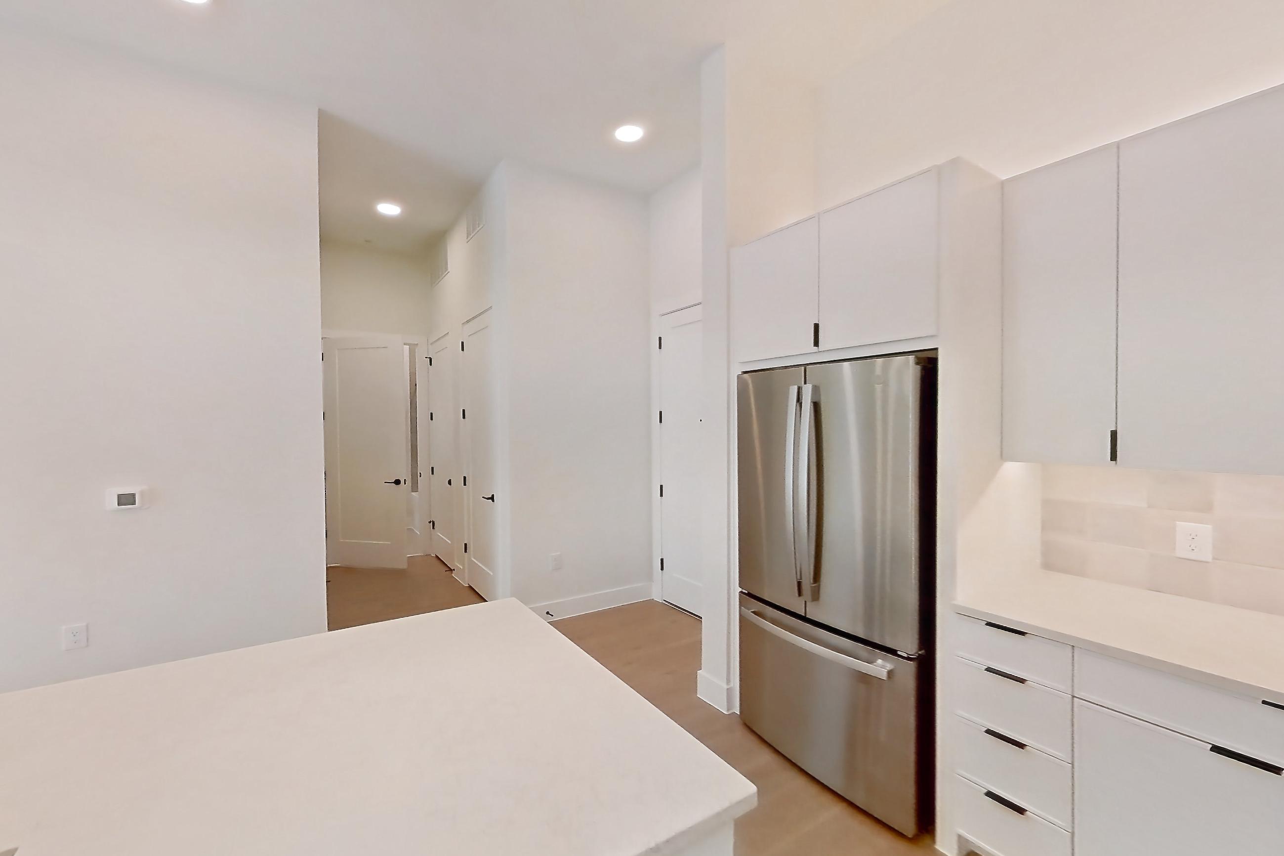 Kitchen with dishwasher, kitchen island, light countertops, light wood-finish flooring, refrigerator, and stainless steel appliances, Apartment 120 at Lantower Midtown