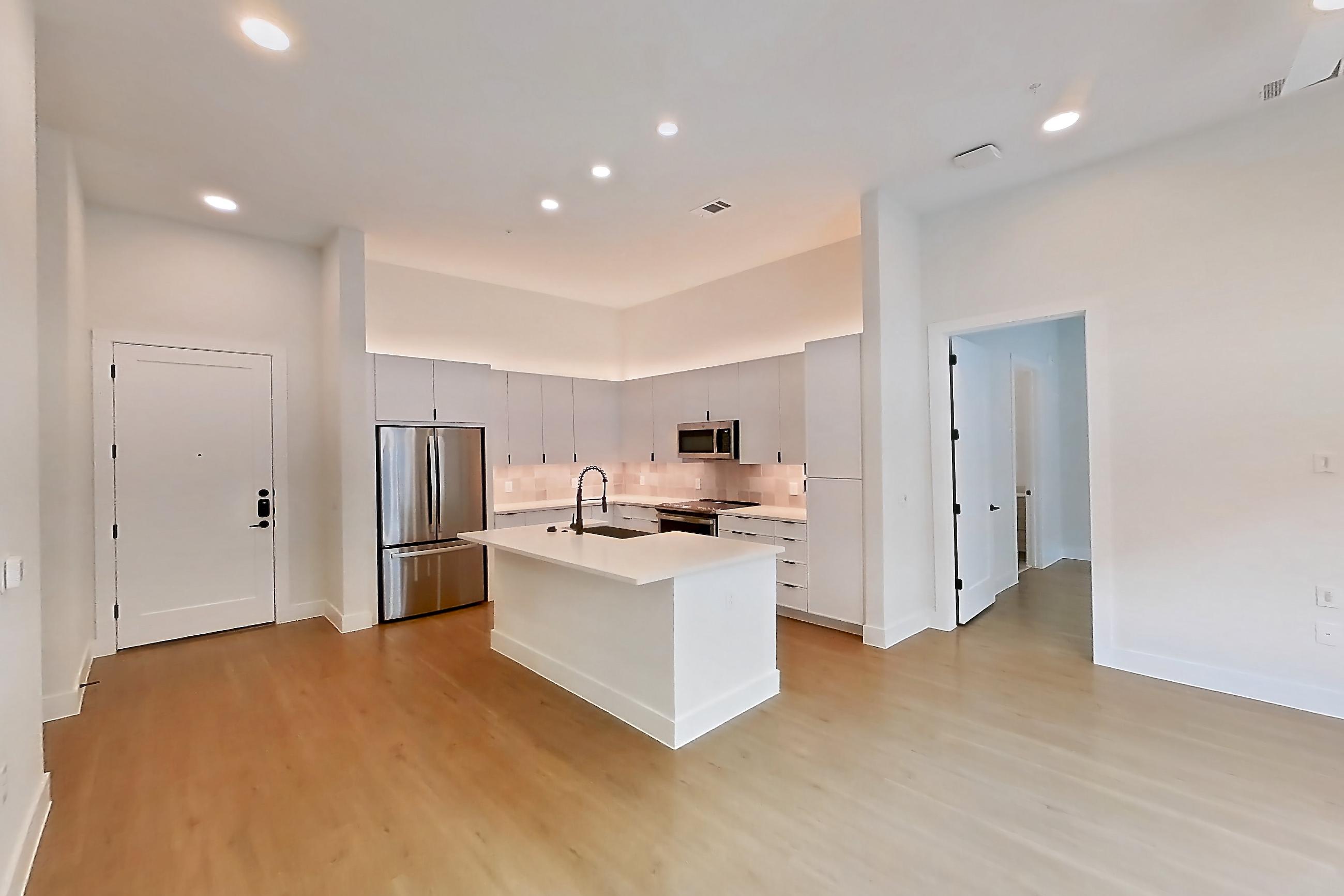 Dining room with electric range, kitchen island, light countertops, light wood-finish flooring, oven/range, refrigerator, and stainless steel appliances, Apartment 121 at Lantower Midtown