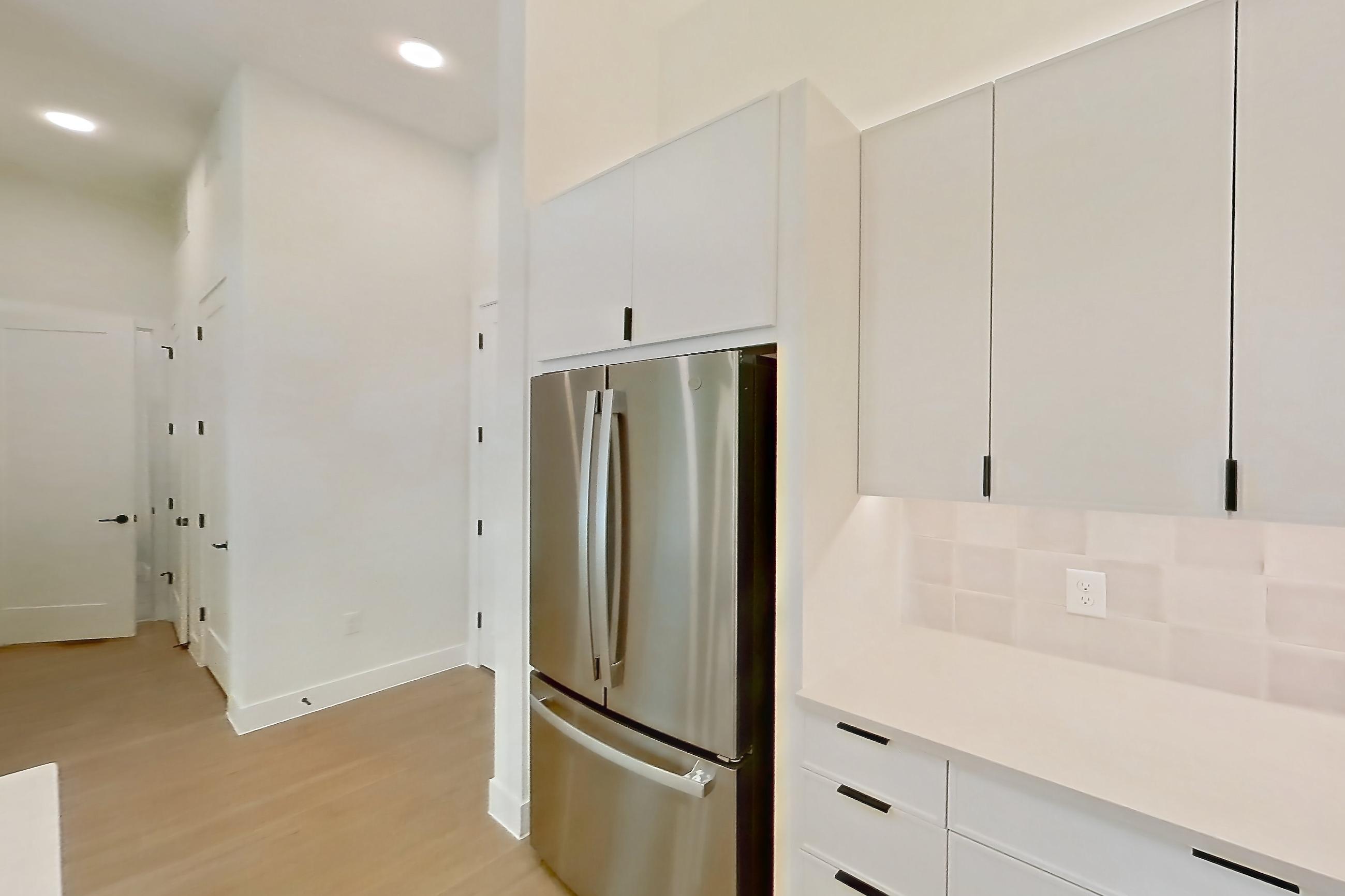 Kitchen with dishwasher, electric range, light countertops, light wood-finish flooring, microwave, oven/range, range hood, refrigerator, and stainless steel appliances, Apartment 121 at Lantower Midtown