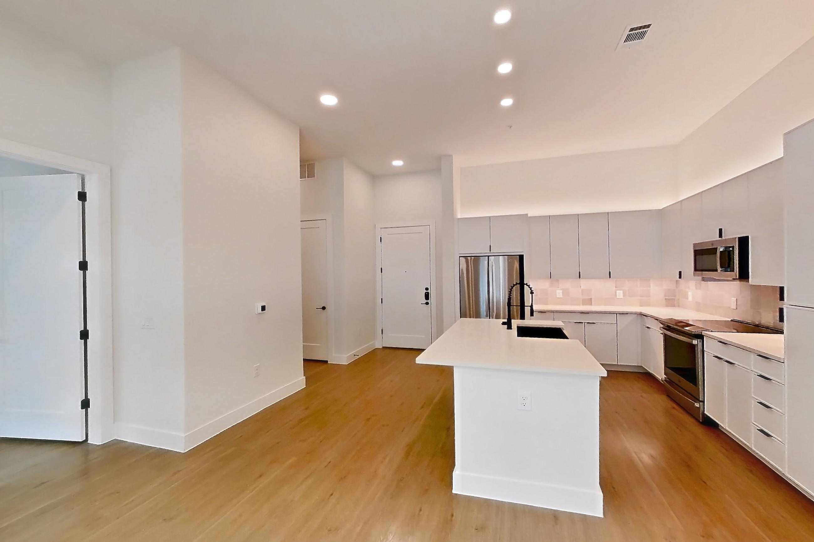 Living room with electric range, light countertops, light wood-finish flooring, oven/range, and stainless steel appliances, Apartment 121 at Lantower Midtown