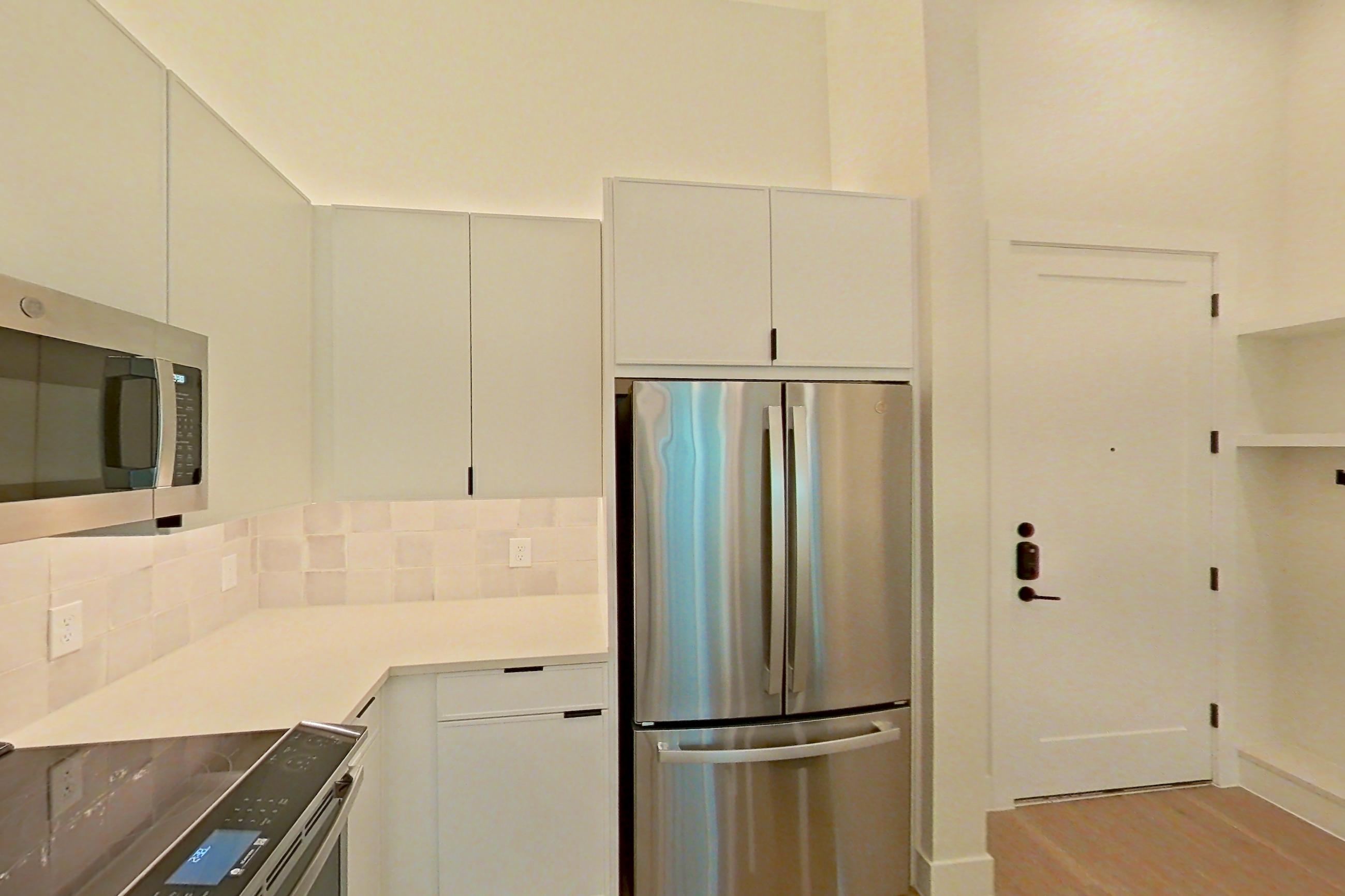 Kitchen with dishwasher, electric range, light countertops, light wood-finish flooring, oven/range, refrigerator, and stainless steel appliances, Apartment 160 at Lantower Midtown