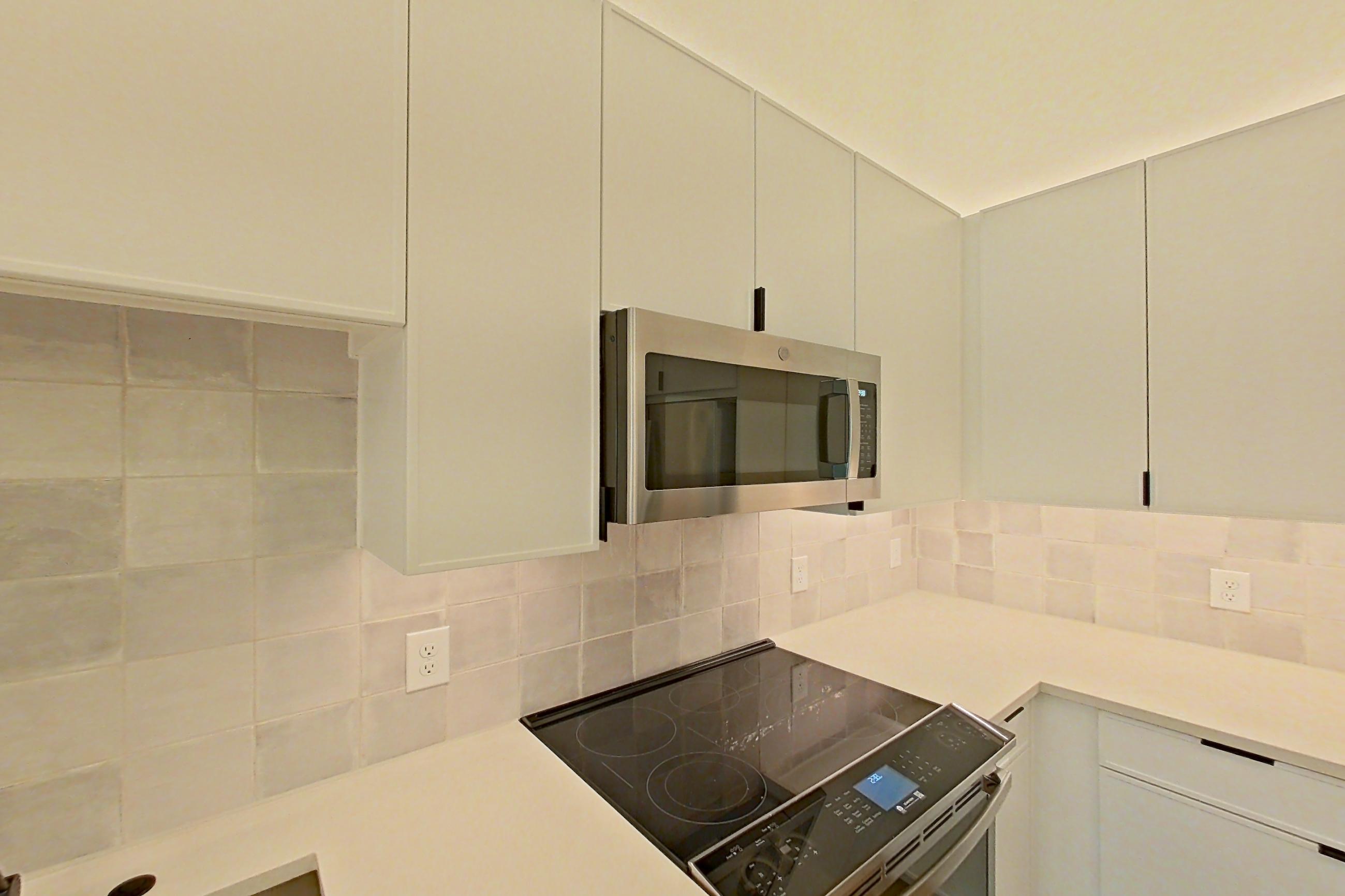 Kitchen with dishwasher, electric range, light countertops, light wood-finish flooring, oven/range, refrigerator, and stainless steel appliances, Apartment 160 at Lantower Midtown