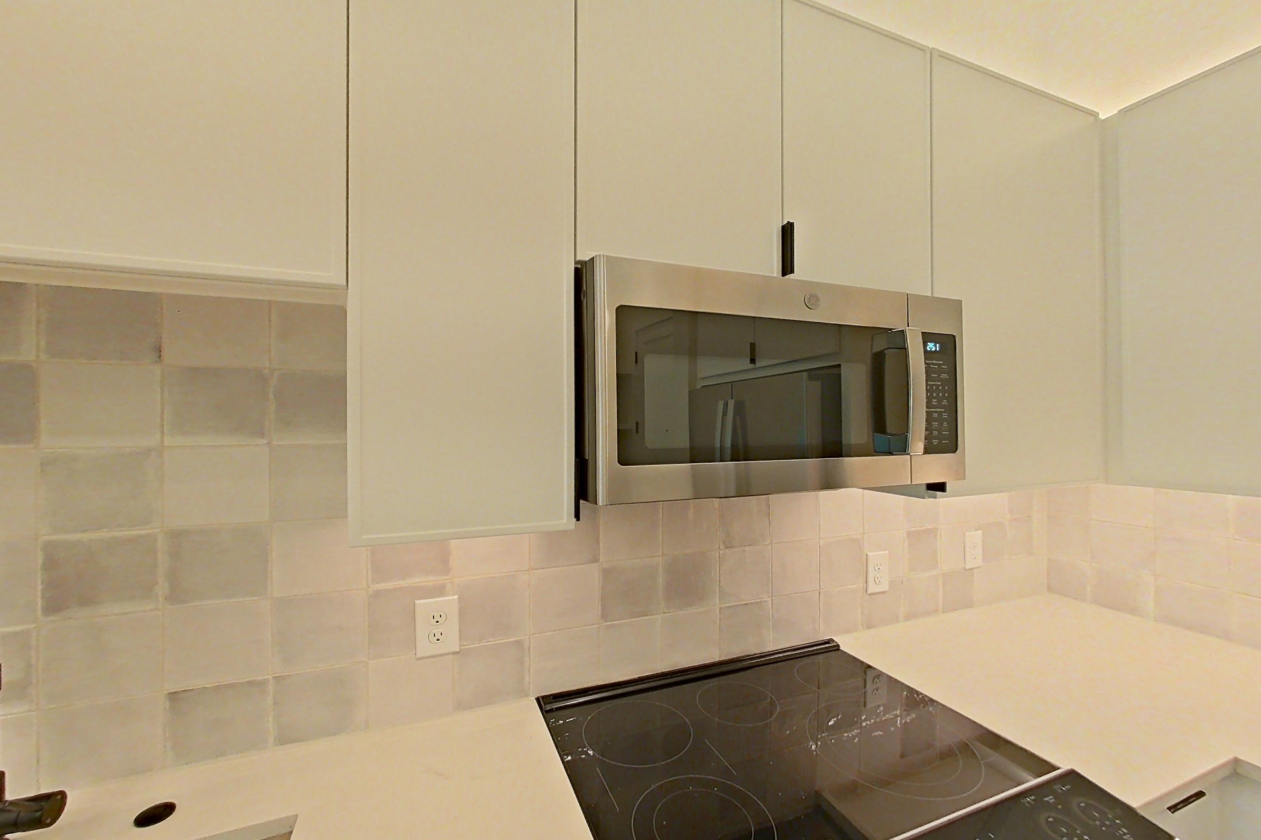 Kitchen with dishwasher, electric range, light countertops, light wood-finish flooring, microwave, oven/range, refrigerator, and stainless steel appliances, Apartment 162 at Lantower Midtown