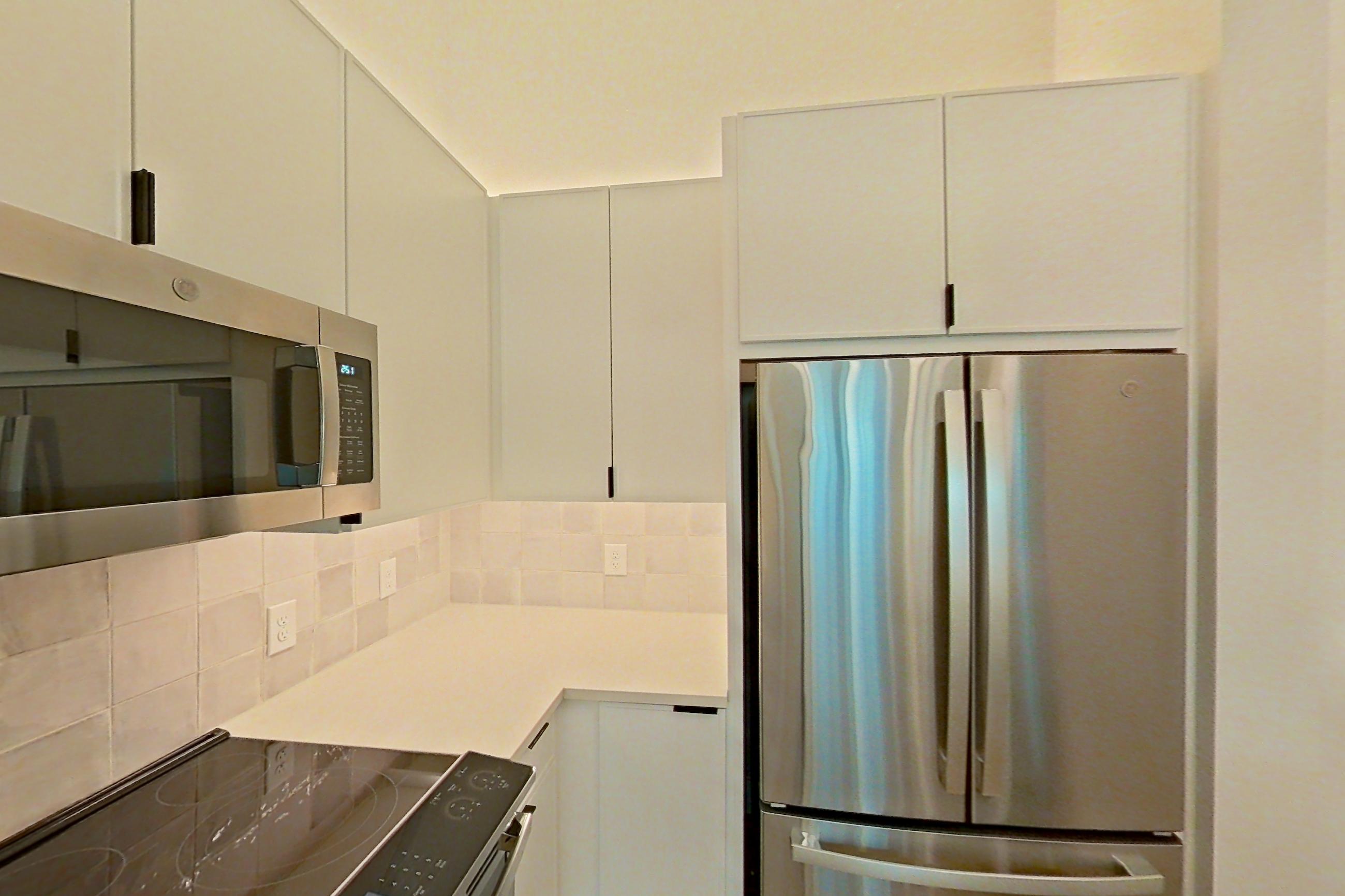 Kitchen with dishwasher, electric range, light countertops, light wood-finish flooring, microwave, oven/range, refrigerator, and stainless steel appliances, Apartment 162 at Lantower Midtown