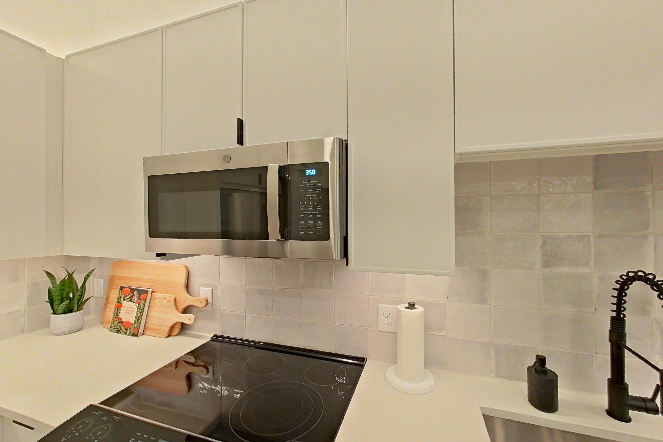 Kitchen with dishwasher, electric range, light countertops, light wood-finish flooring, microwave, refrigerator, and stainless steel appliances, Apartment 172 at Lantower Midtown