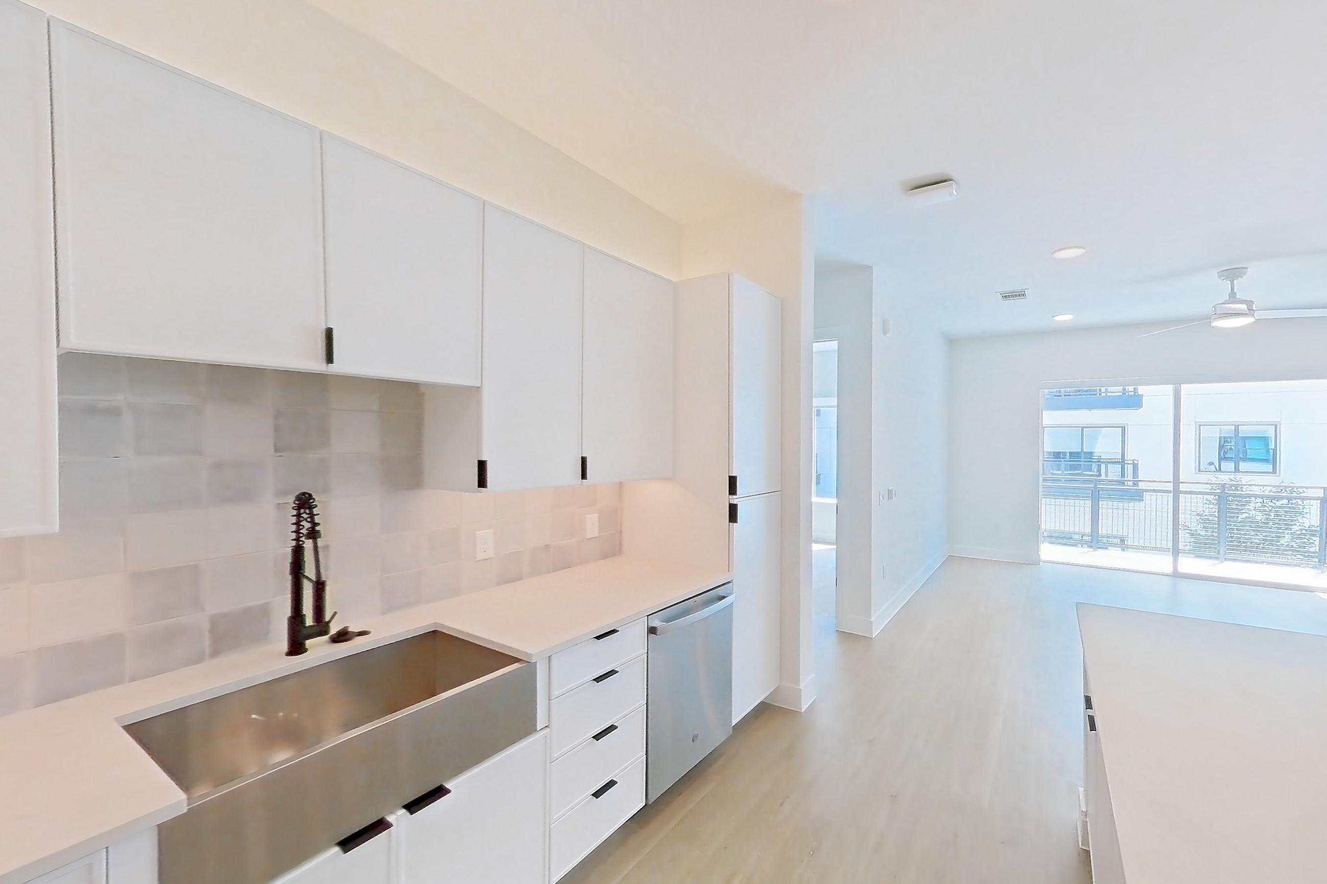 Kitchen with dishwasher, electric range, light countertops, light stone countertops, light wood-finish flooring, microwave, oven/range, refrigerator, and stainless steel appliances, Apartment 266 at Lantower Midtown