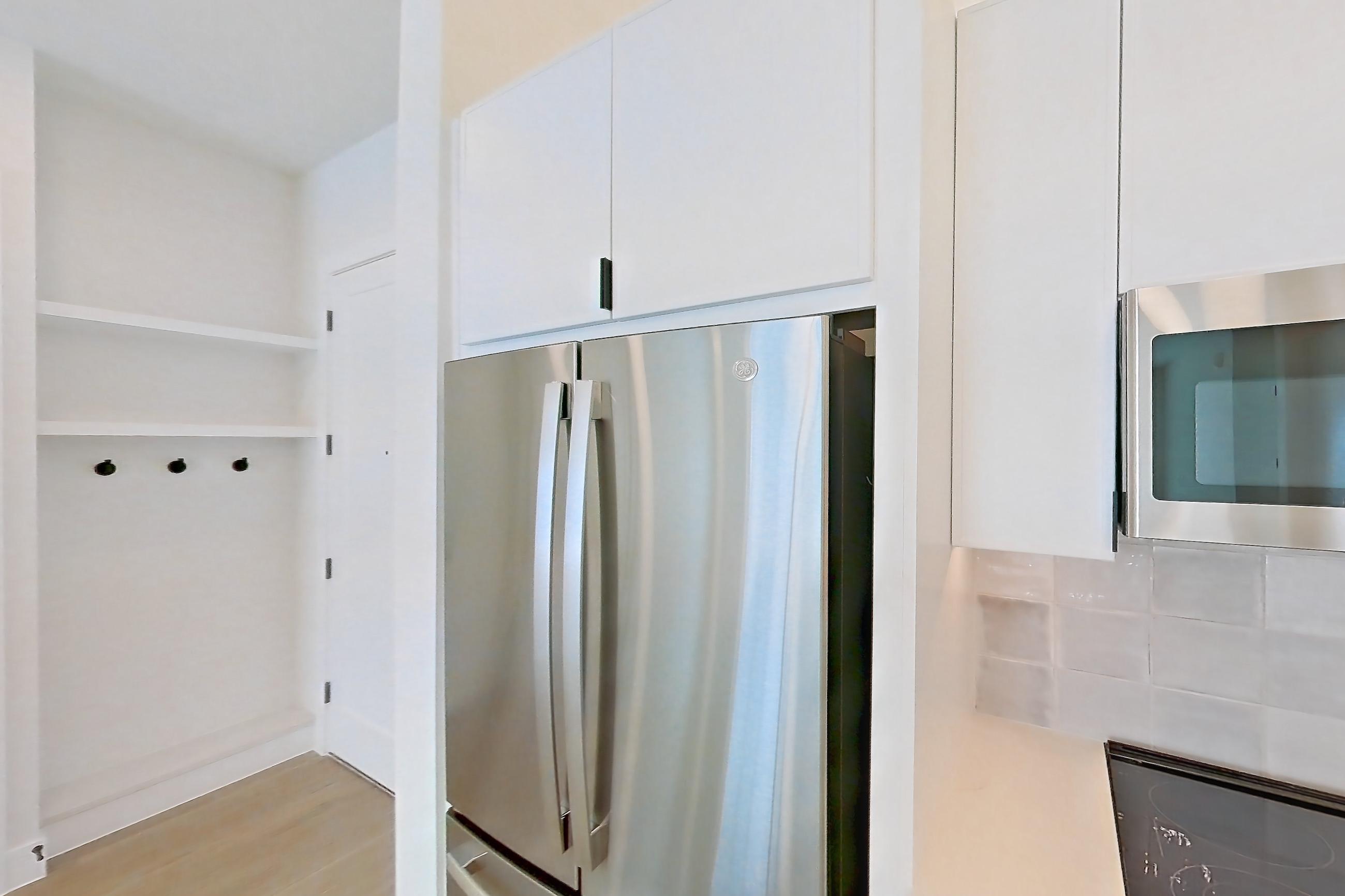 Kitchen with dishwasher, electric range, light countertops, light stone countertops, light wood-finish flooring, microwave, oven/range, refrigerator, and stainless steel appliances, Apartment 266 at Lantower Midtown