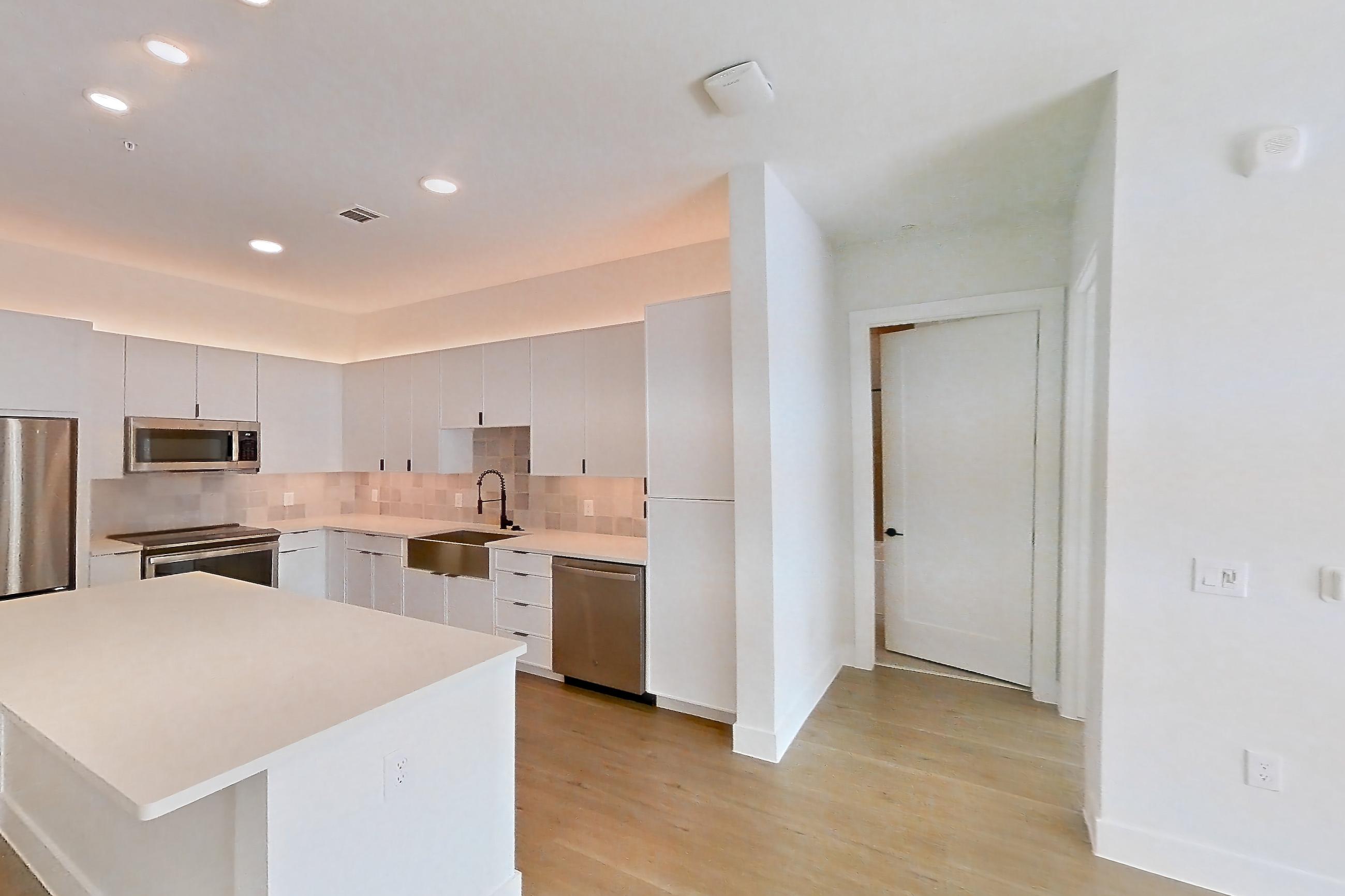 Living room with dishwasher, light wood-finish flooring, and stainless steel appliances, Apartment 266 at Lantower Midtown
