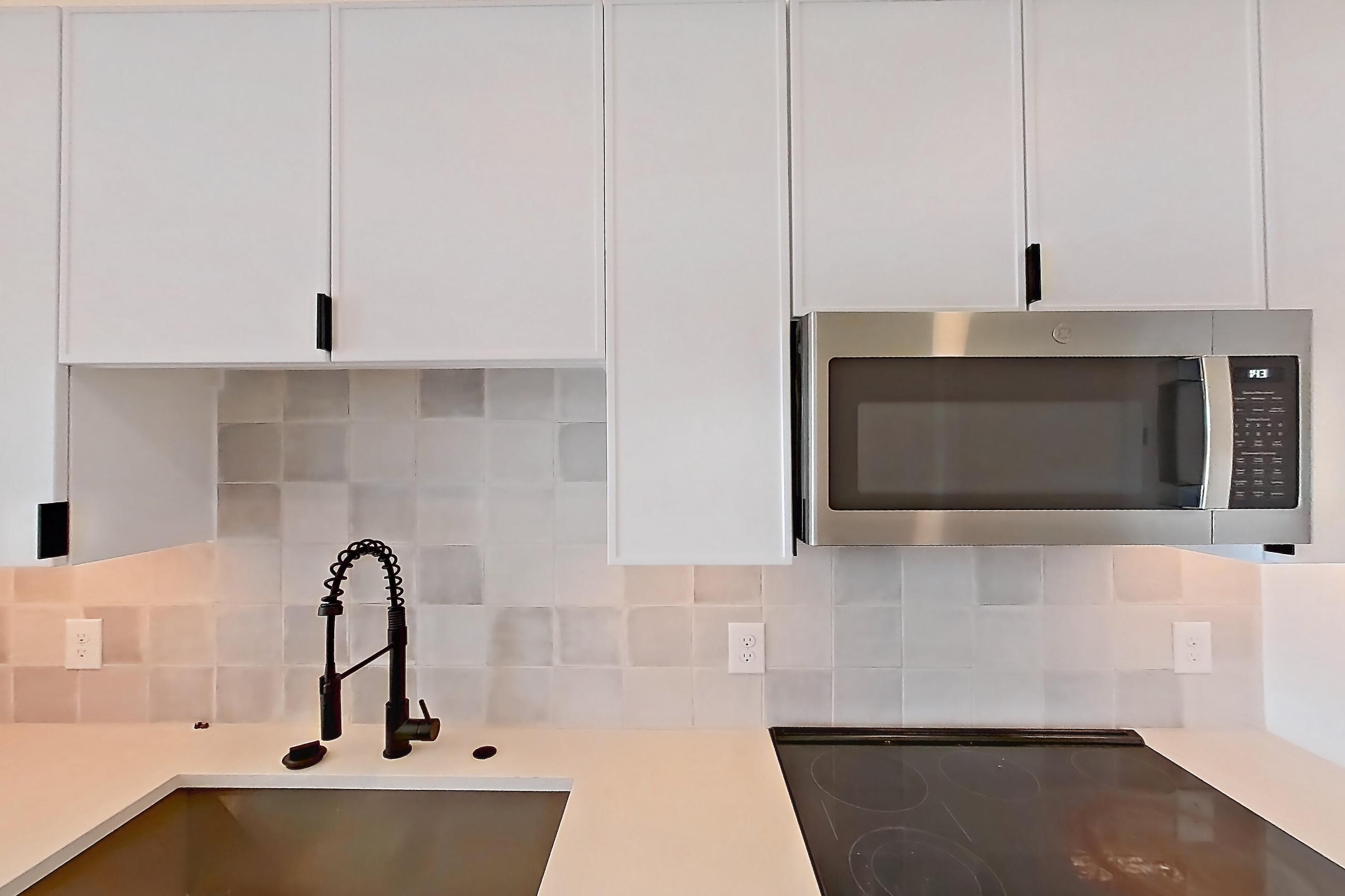 Kitchen with dishwasher, electric range, light countertops, light stone countertops, light wood-finish flooring, microwave, oven/range, refrigerator, stainless steel appliances, and wood-finish flooring, Apartment 314 at Lantower Midtown