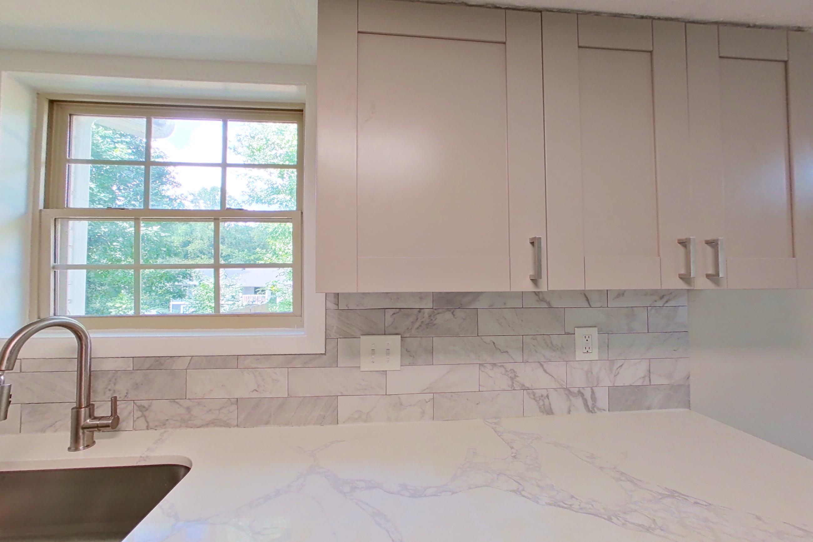 Kitchen with dishwasher, electric range, light stone countertops, light wood-finish flooring, microwave, refrigerator, and stainless steel appliances, Apartment 2303 at Dunwoody Glen