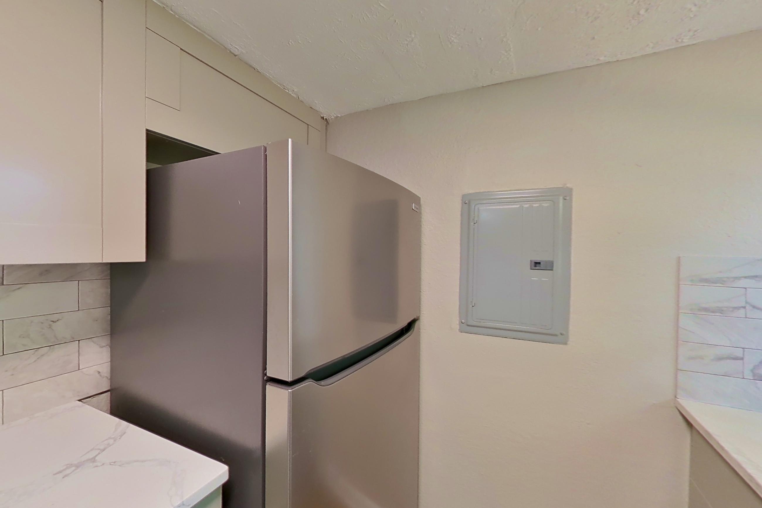 Kitchen with dishwasher, electric range, light stone countertops, light wood-finish flooring, microwave, refrigerator, and stainless steel appliances, Apartment 2303 at Dunwoody Glen
