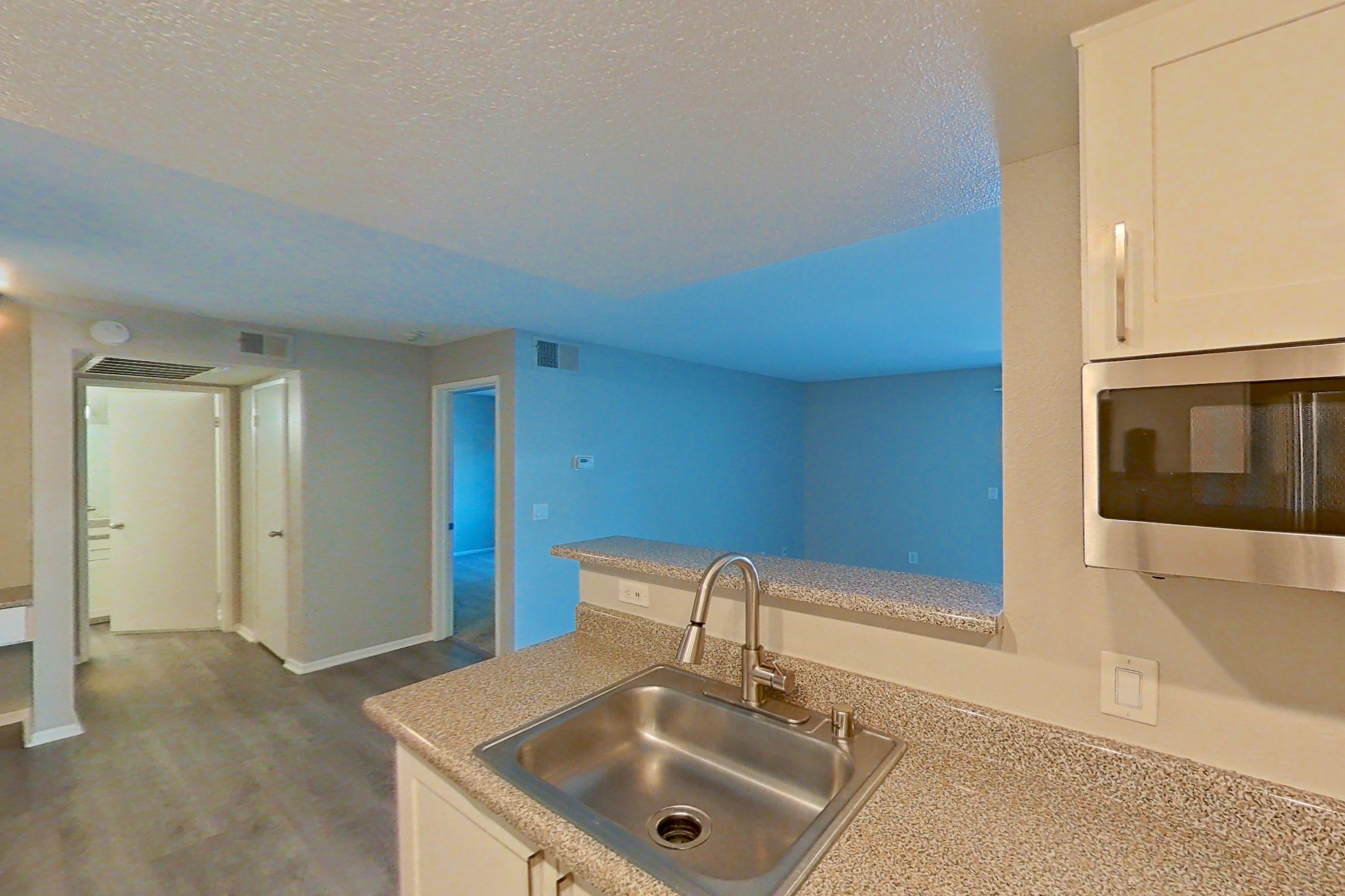 Kitchen with dishwasher, electric range, light countertops, light stone countertops, light wood-finish flooring, oven/range, range hood, refrigerator, and stainless steel appliances, Apartment 07 at Avana Rancho Cucamonga