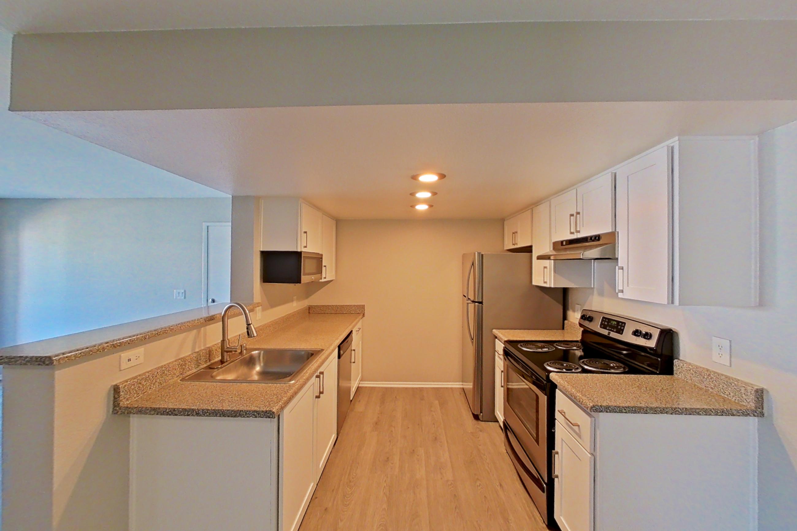 Dining area with dishwasher, electric range, light stone countertops, light wood-finish flooring, oven/range, and stainless steel appliances, Apartment 11 at Avana Rancho Cucamonga